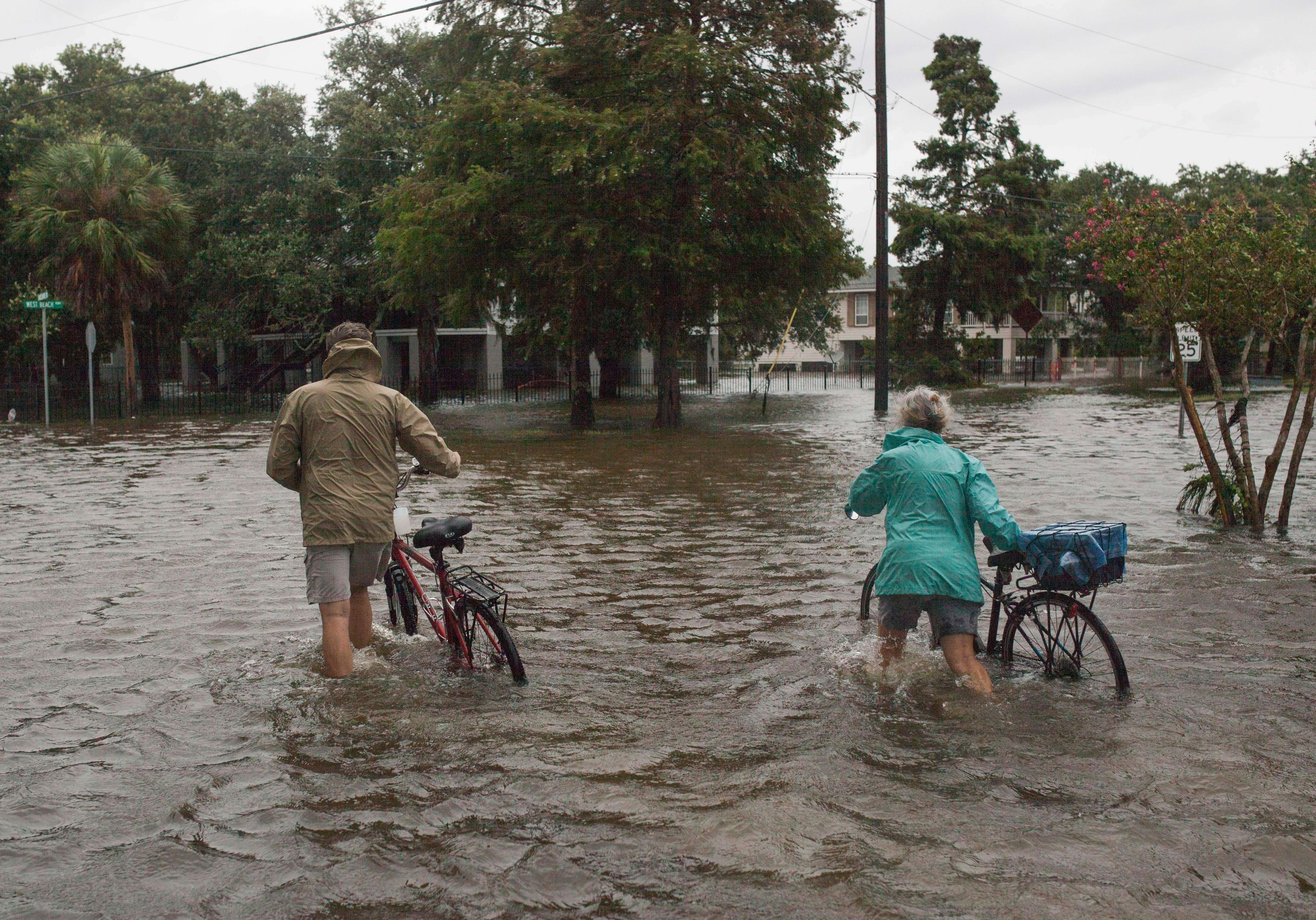  A couple walks their bikes through a flooded street after Tropical Storm Barry came ashore in Mandeville, Louisiana.