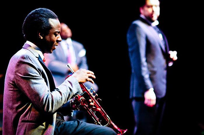 Omar El-Amin as Miles Davis, holding trumpet.