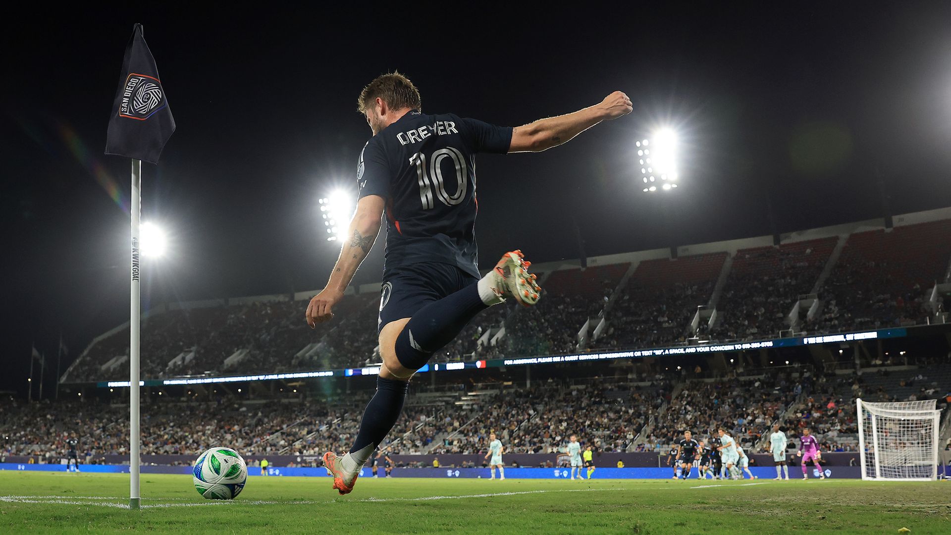 SDFC player Anders Dreyer kicks a corner kick during a game at night at Snapdragon Stadium.