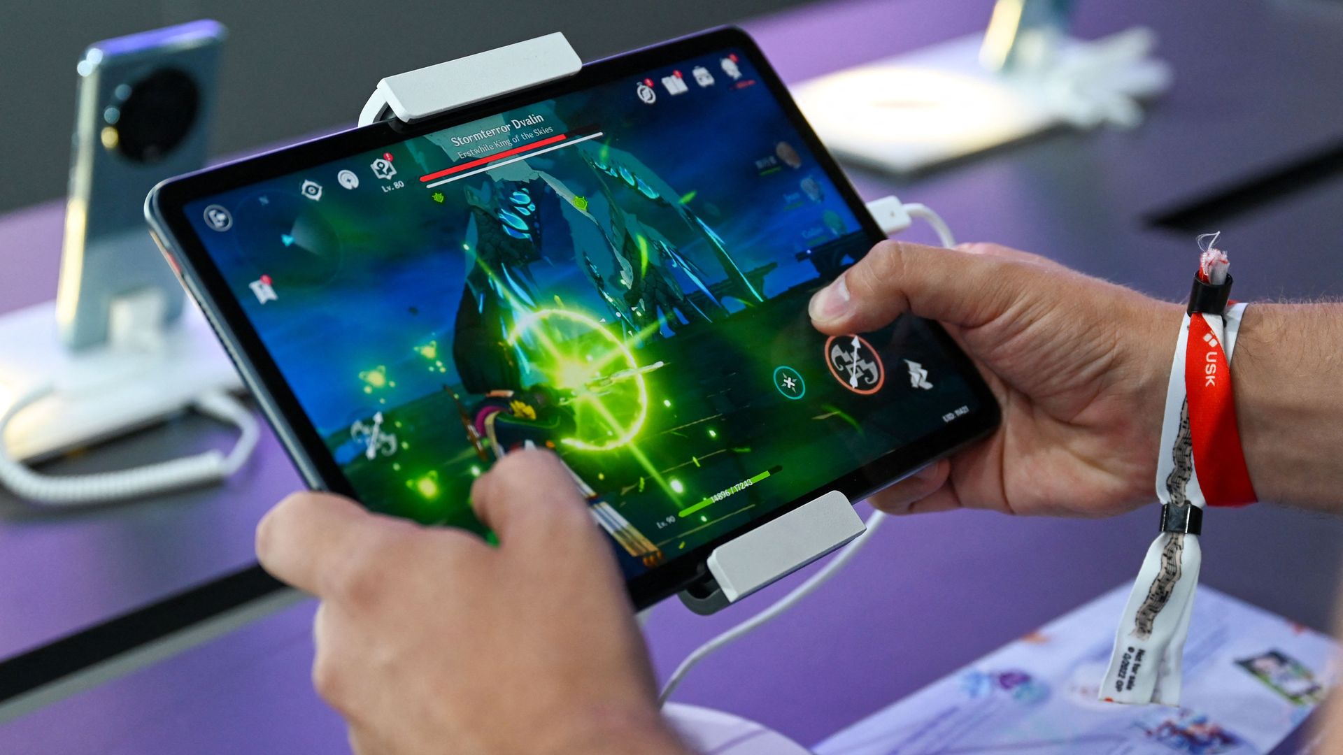 Close-up photo of person's hands and the tablet they're playing a video game on