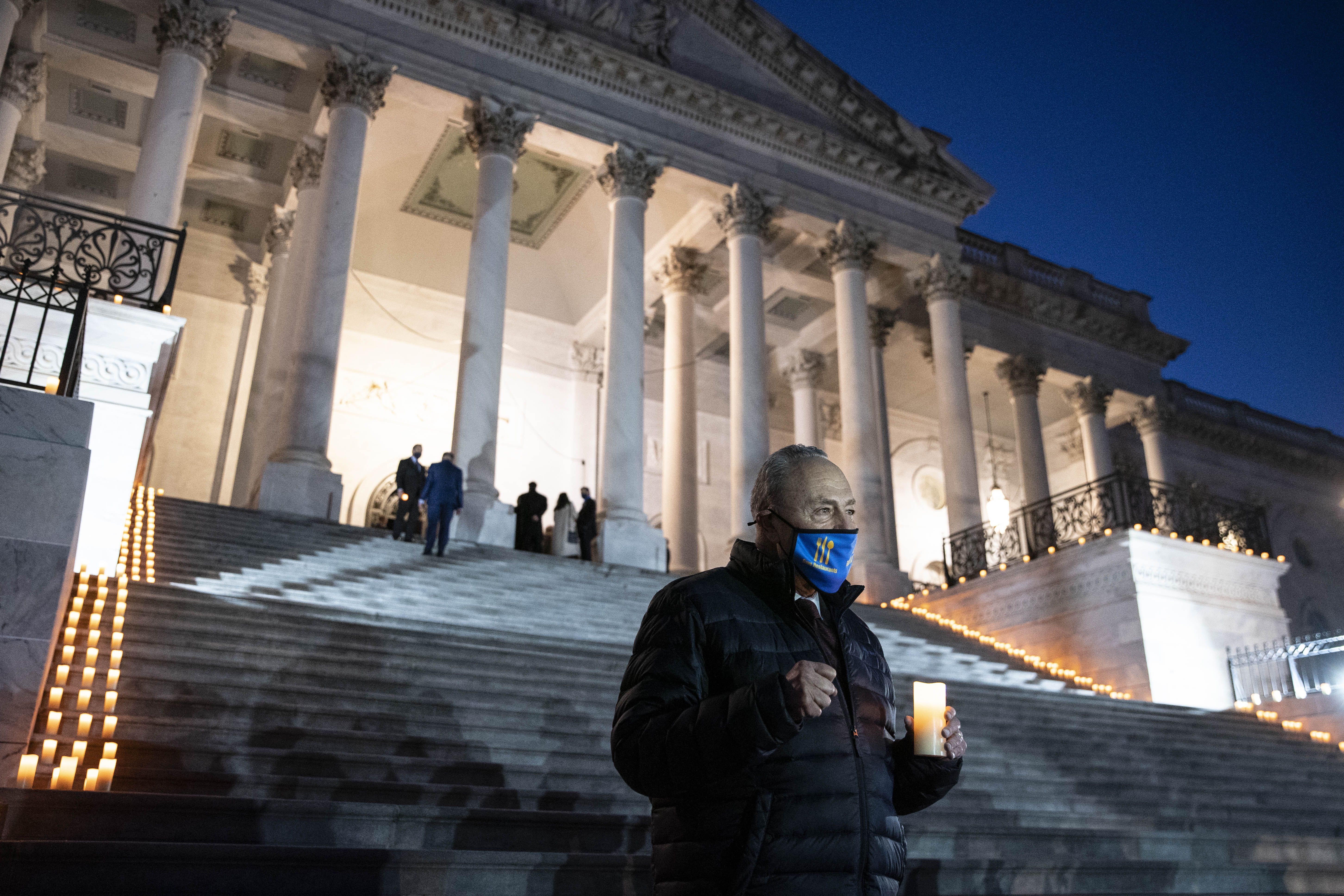 Senate Majority Leader Chuck Schumer holding a candle outside of the Capitol on Feb. 23.