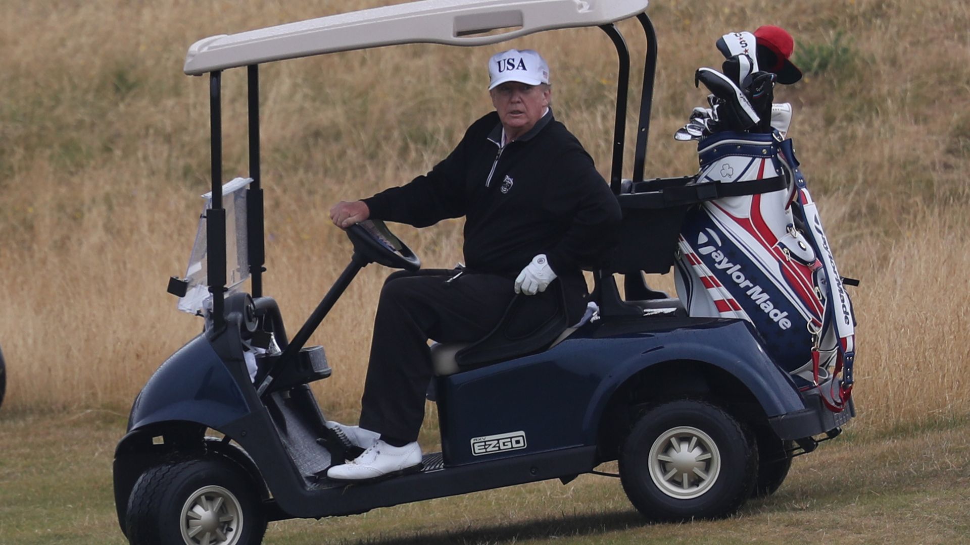 Trump riding a golf wagon.