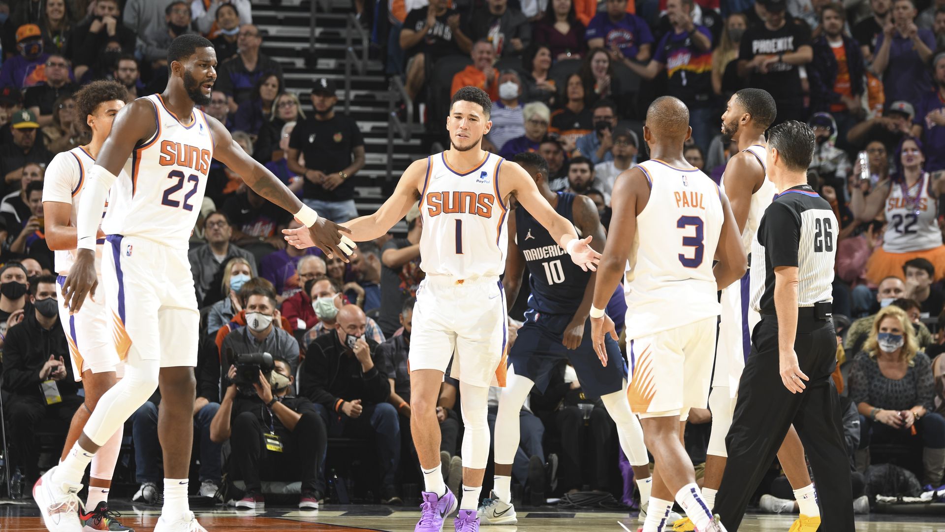 Phoenix Suns player Devin Booker high fives teammates Chris Paul and Deandre Ayton
