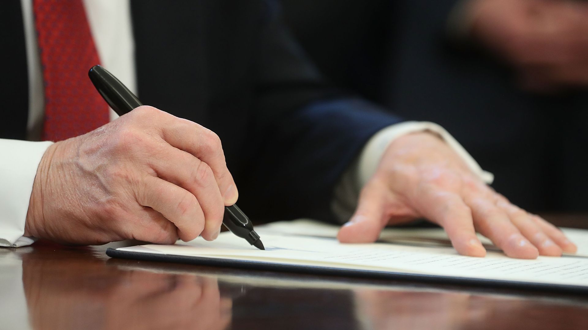Up-close photo of Trump signing a document with a black Sharpie.