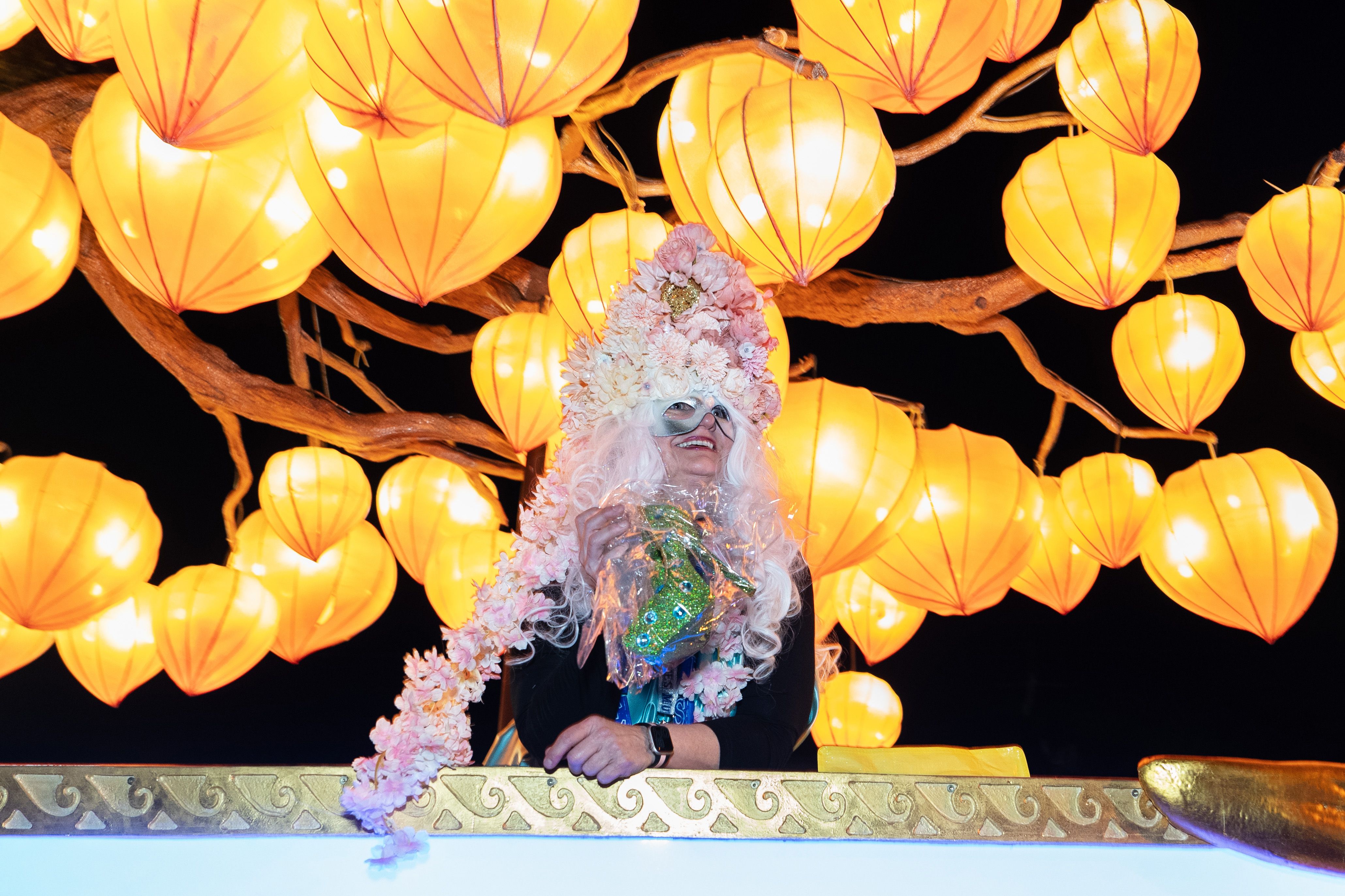 Photo shows a woman riding on a Krewe of Muses float
