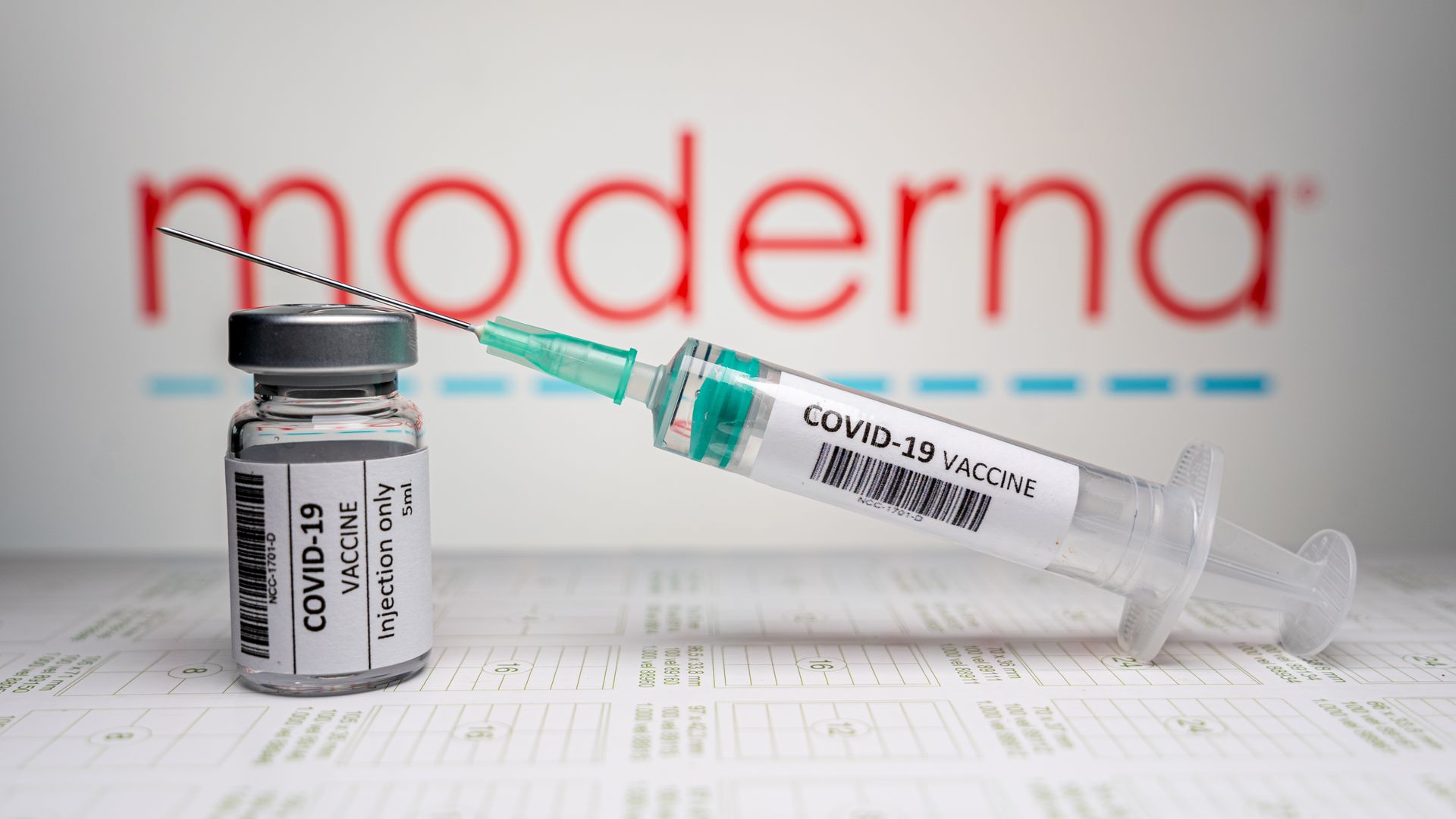 picture of a coronavirus vaccine syringe in front of a moderna sign