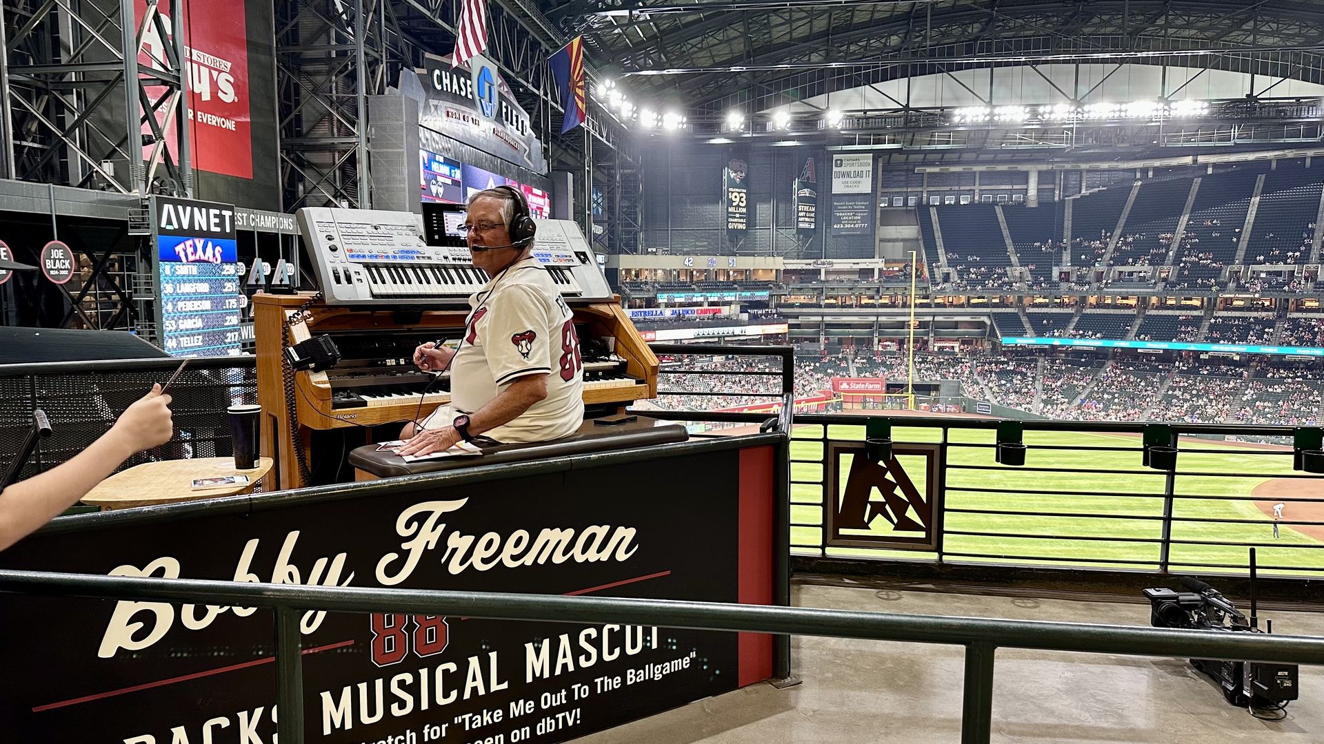 A man wearing a white baseball jersey with number 88 plays the organ at a stadium