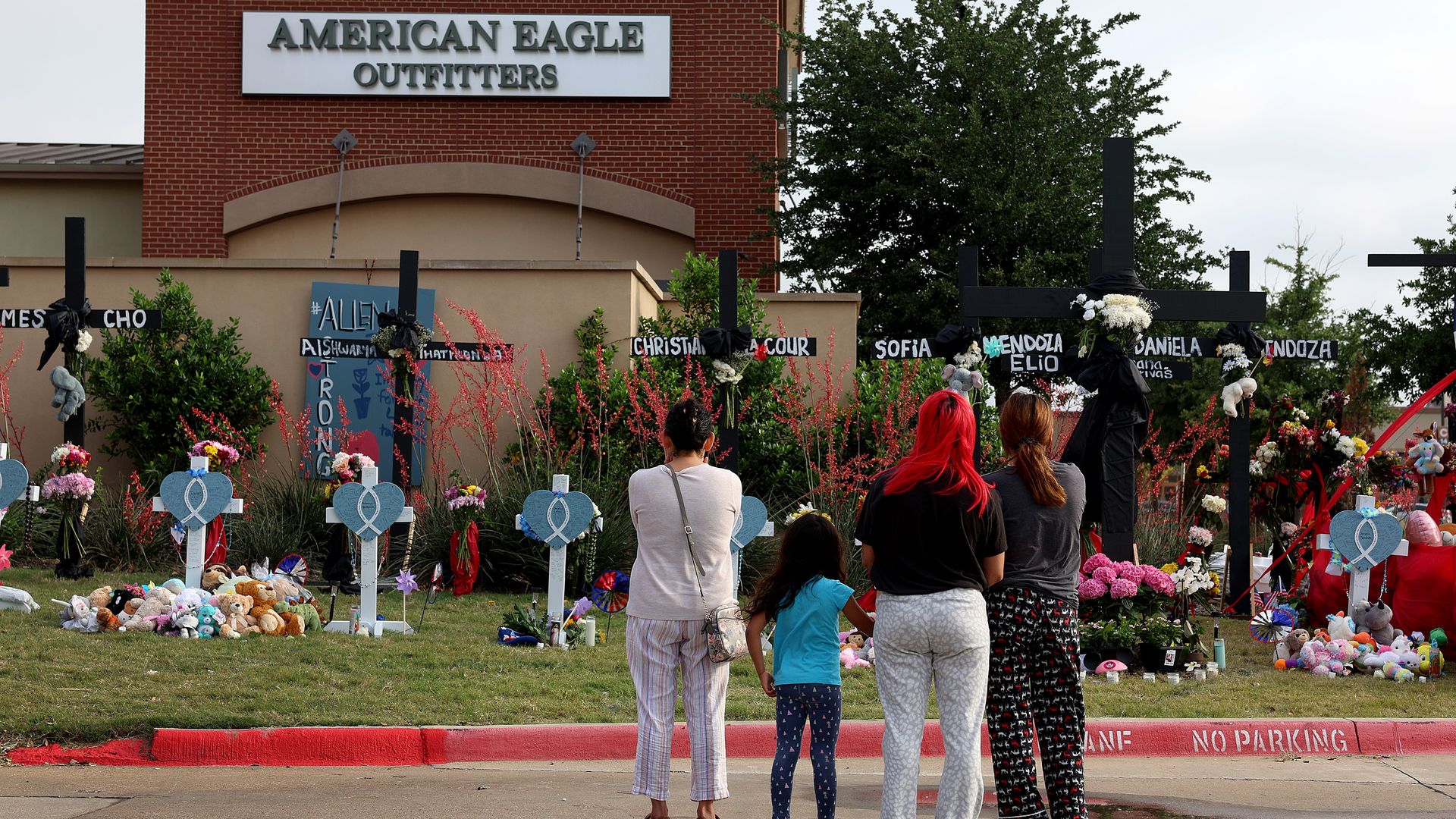 Four people stand in front of makeshift memorials for the people killed in a mass shooting in Allen