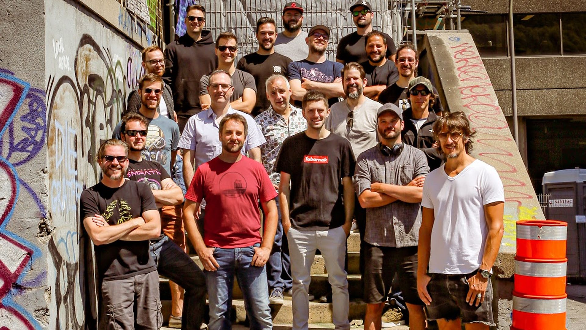 Photograph of a group of game developers standing on a staircase. All are white men.