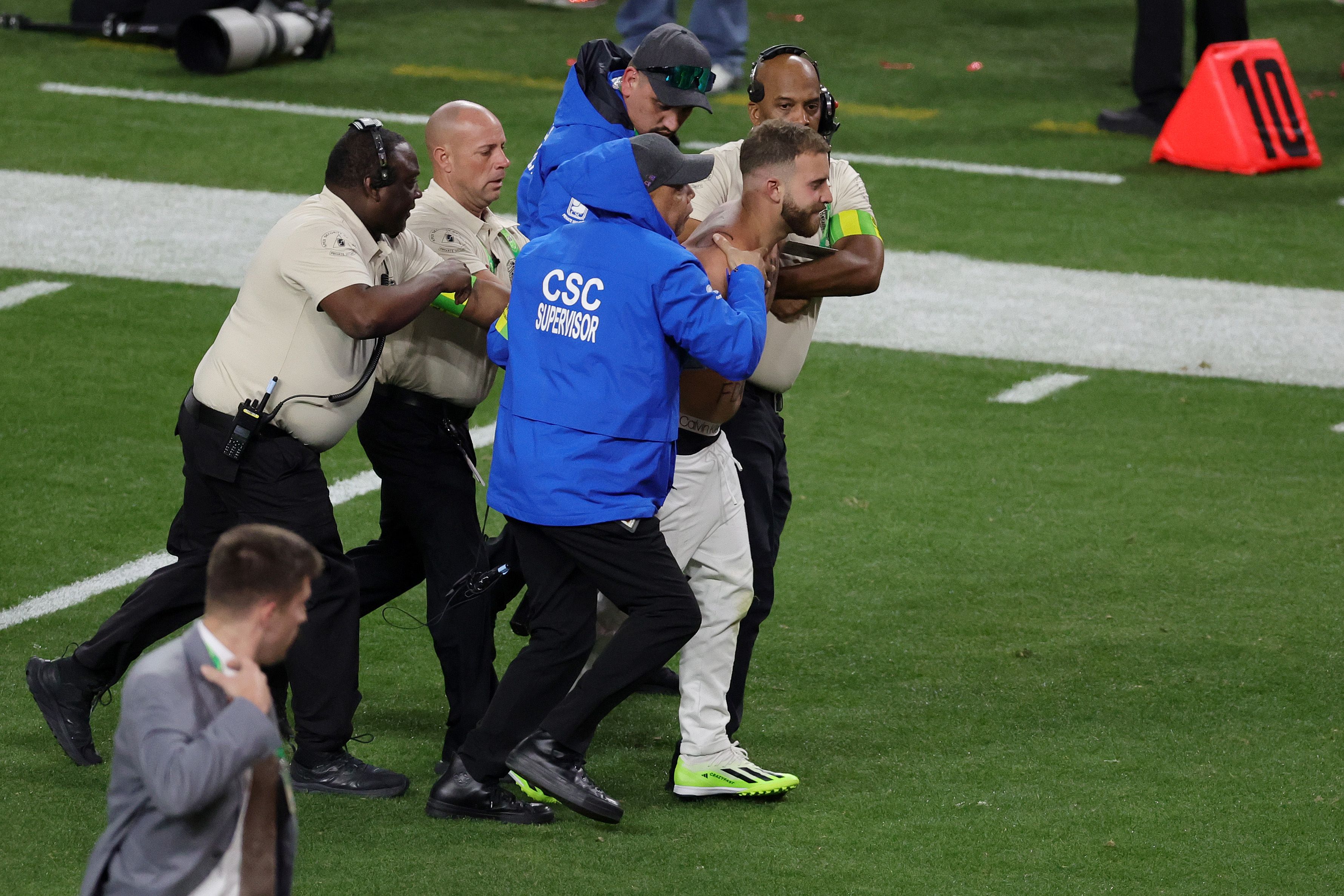 A fan is escorted away after running onto the field in the third quarter during Super Bowl LVIII between the San Francisco 49ers and Kansas City Chiefs at Allegiant Stadium on February 11, 2024 in Las Vegas, Nevada. 