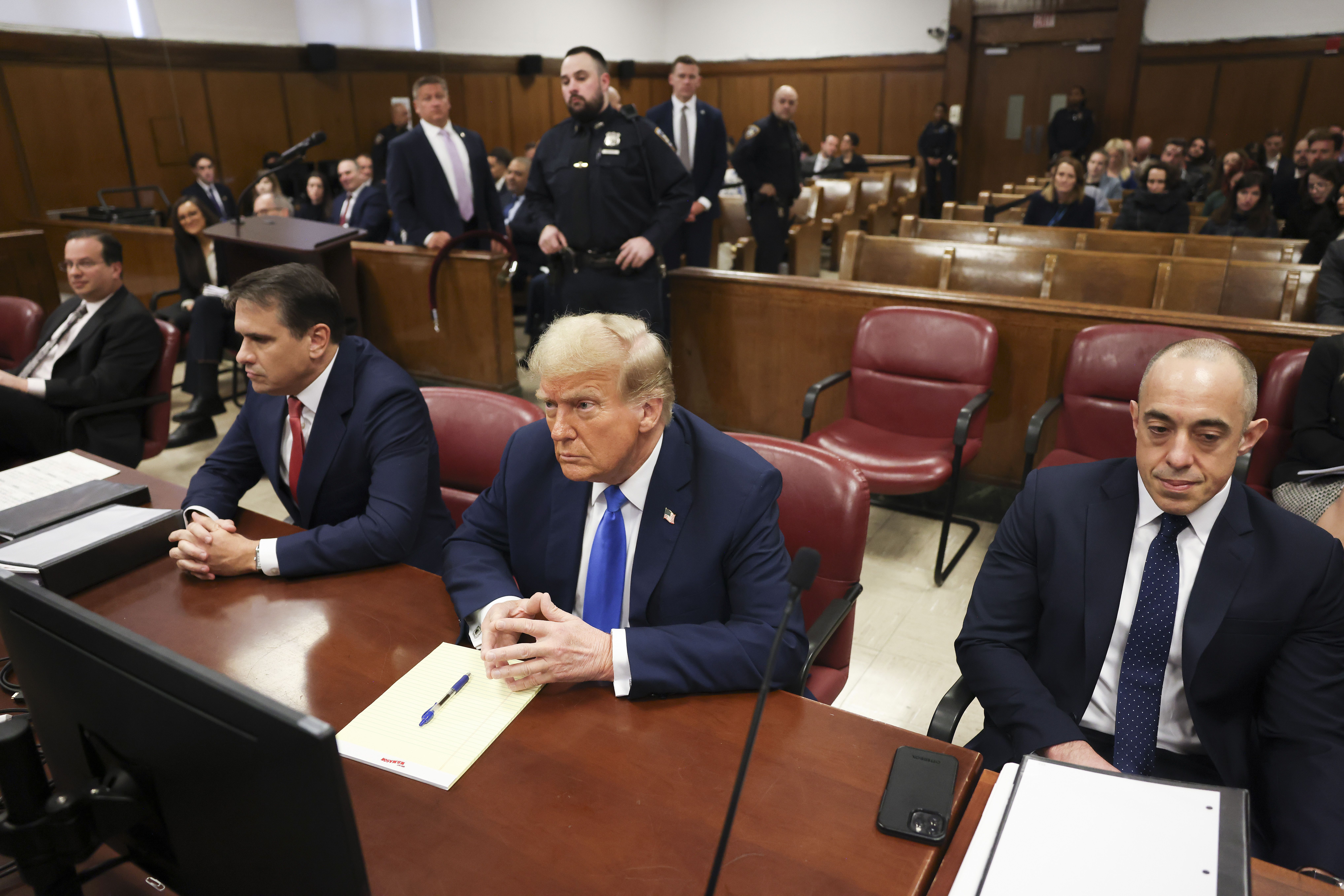 Former president Donald Trump, center, awaits the start of proceedings at Manhattan criminal court, Monday, April 22, 2024, in New York. Opening statements in Donald Trump's historic hush money trial are set to begin. Trump is accused of falsifying internal business records as part of an alleged scheme to bury stories he thought might hurt his presidential campaign in 2016