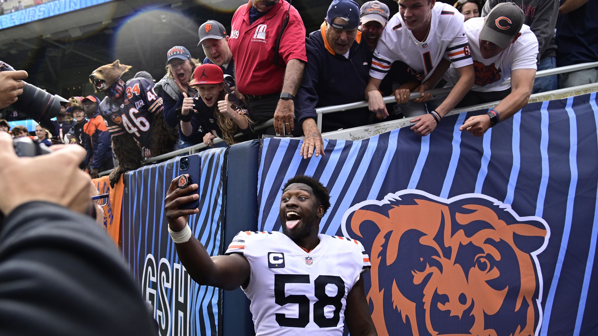 A football player takes a selfie with fans.