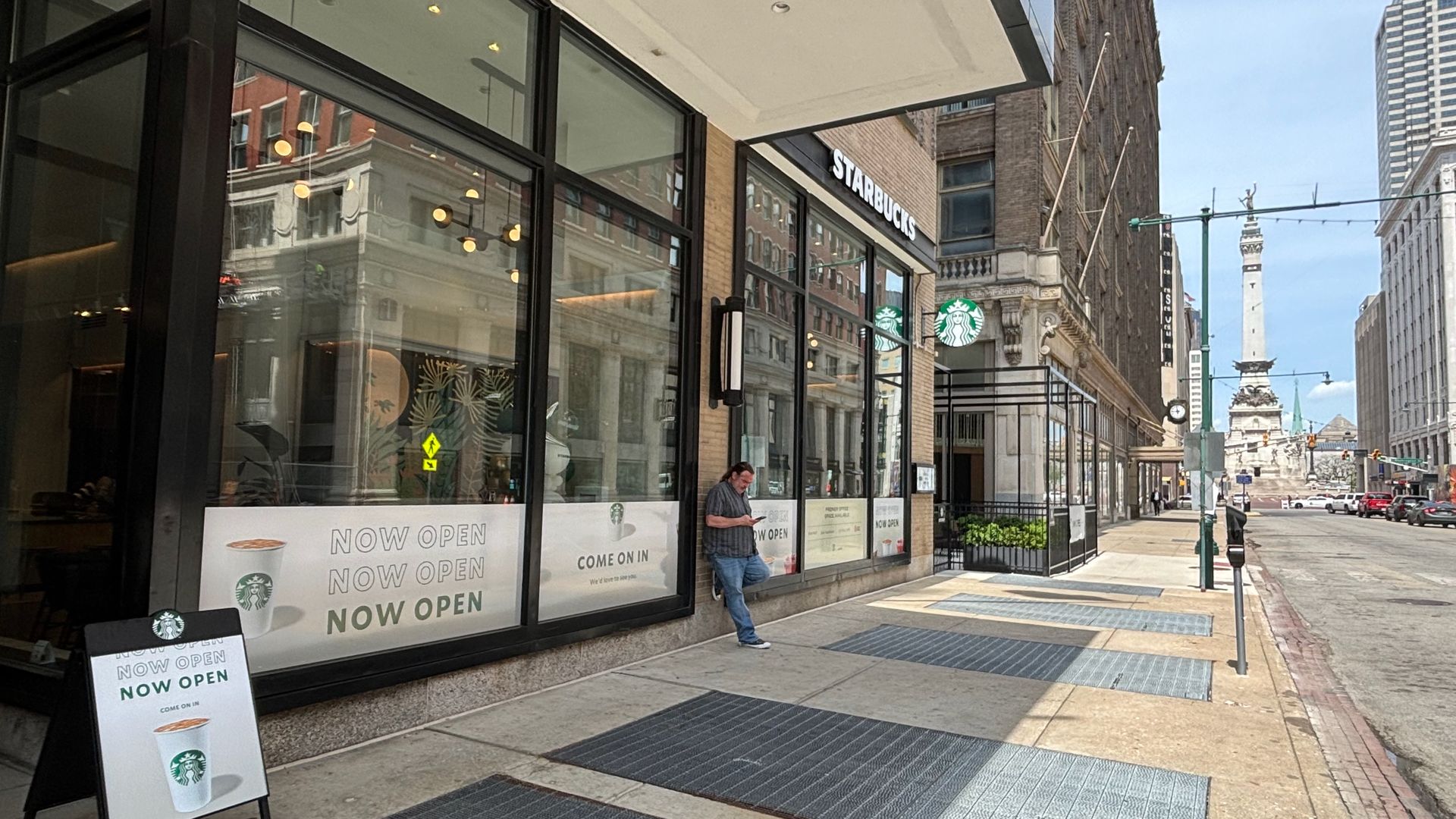 A Starbucks with a now open sign with the monument in the background