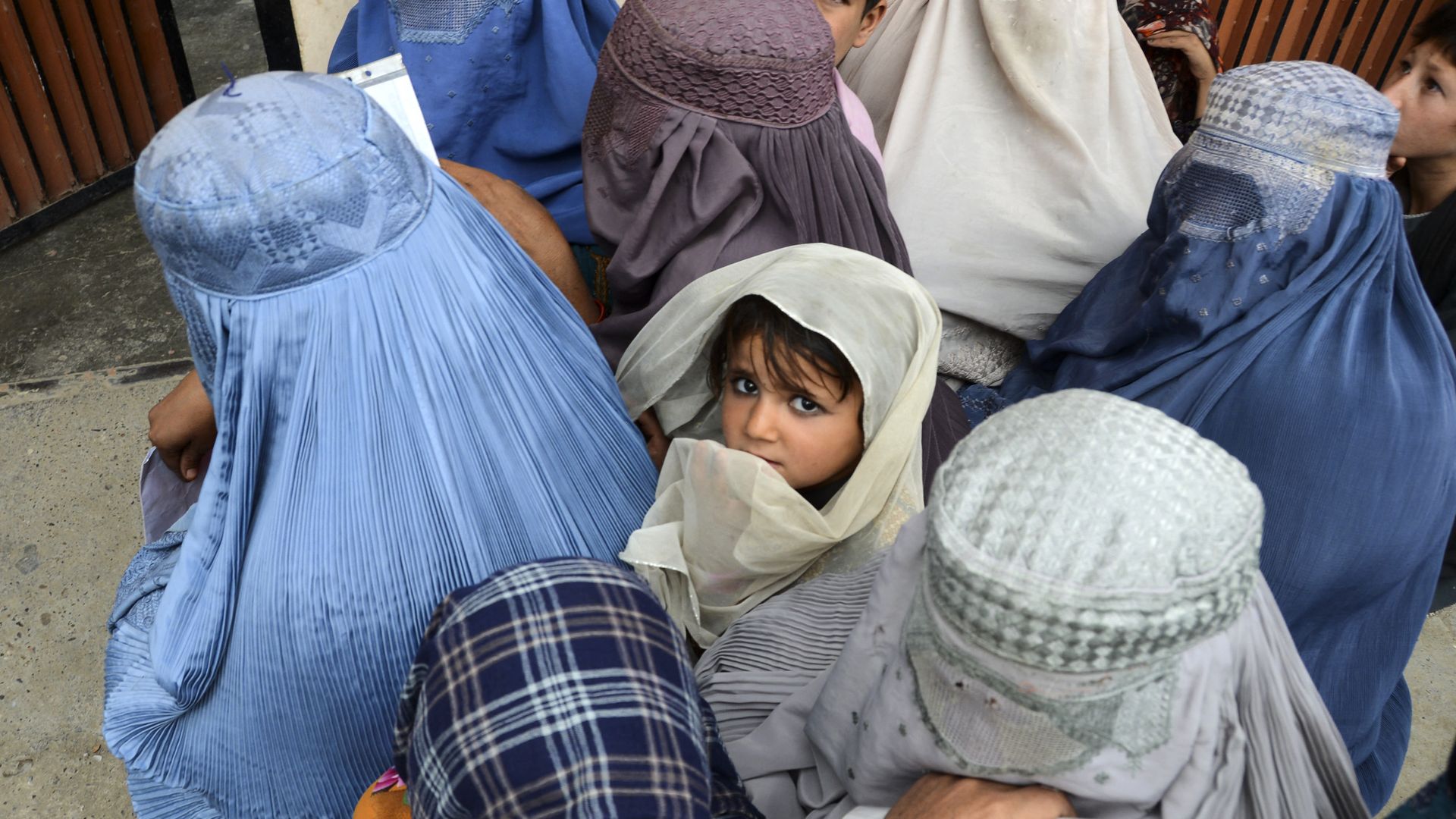Women with children gather outside a United Nations High Commissioner for Refugees (UNHCR) office as they wait to receive non-food items in Kandahar