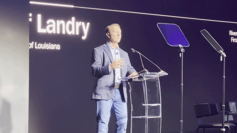 Landry speaks at a clear podium onstage.