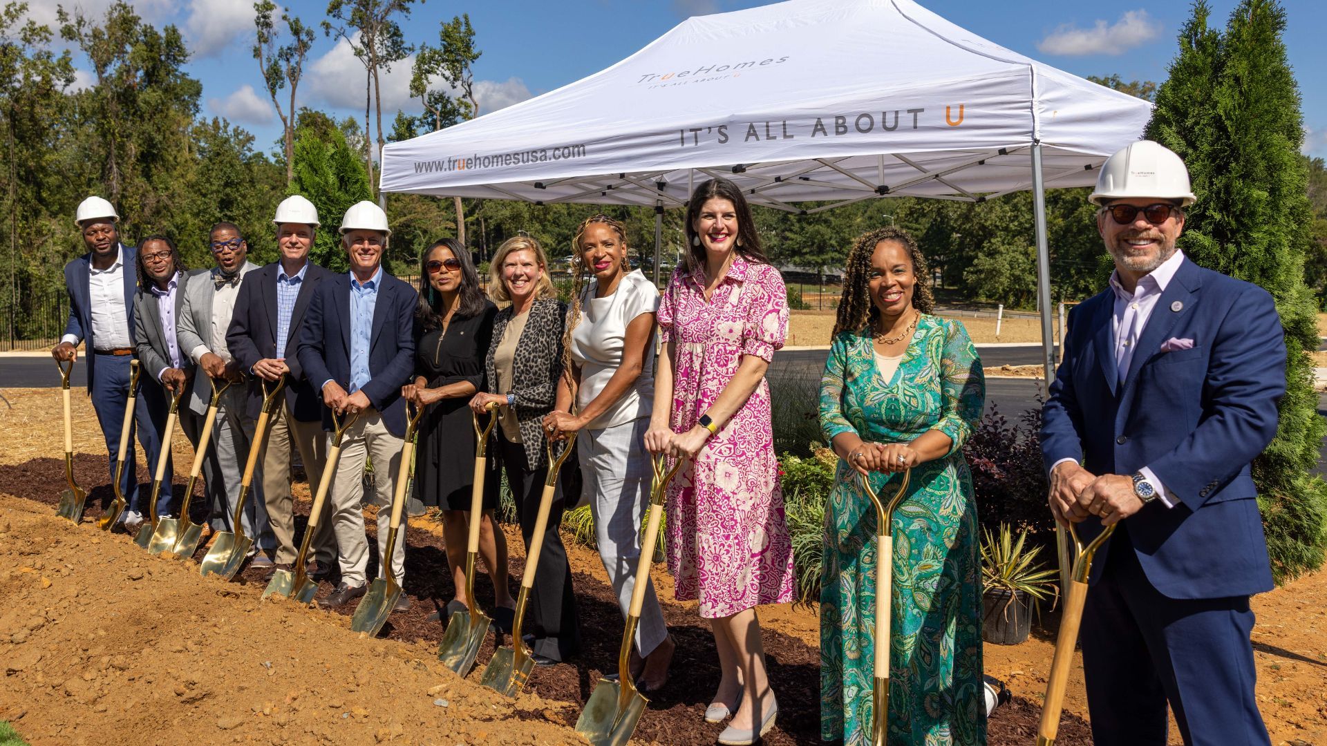 People in business clothes holding shovels. 