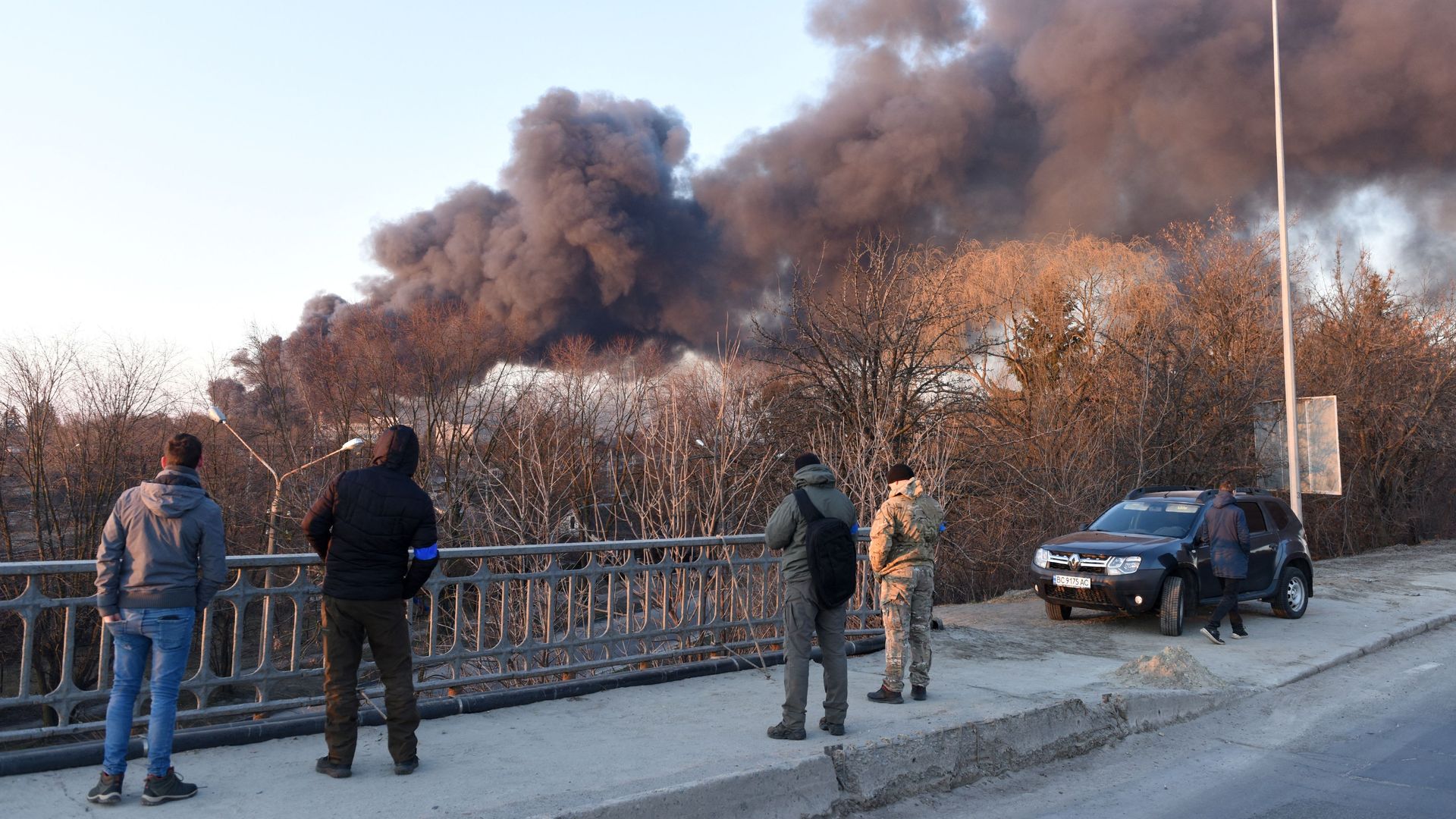 People watching smoke rising over Lviv after Russian forces struck an aircraft repair plant near the city's airport on March 18.