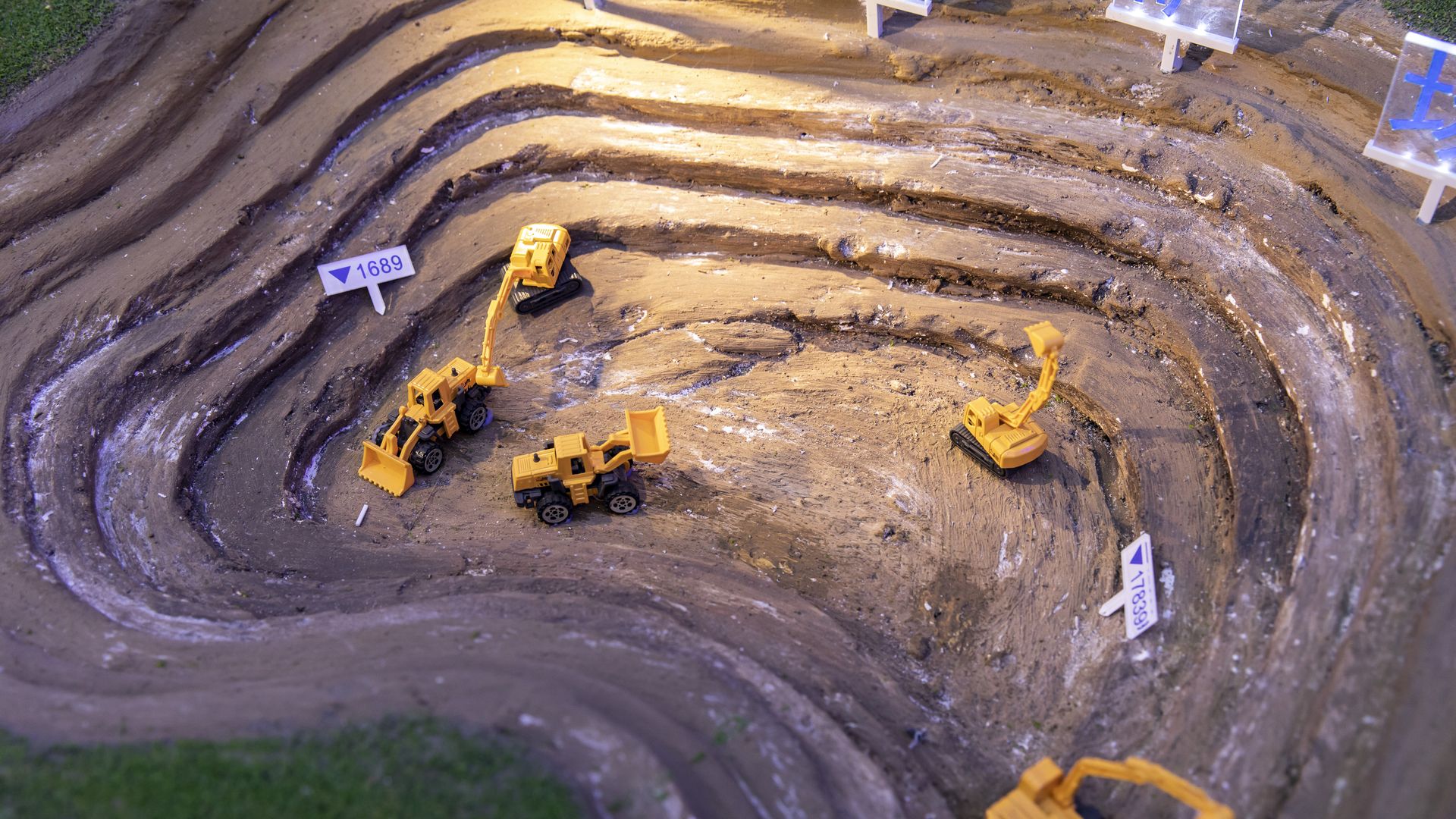 Construction site with four yellow excavators and loaders working in a tiered dirt pit.
