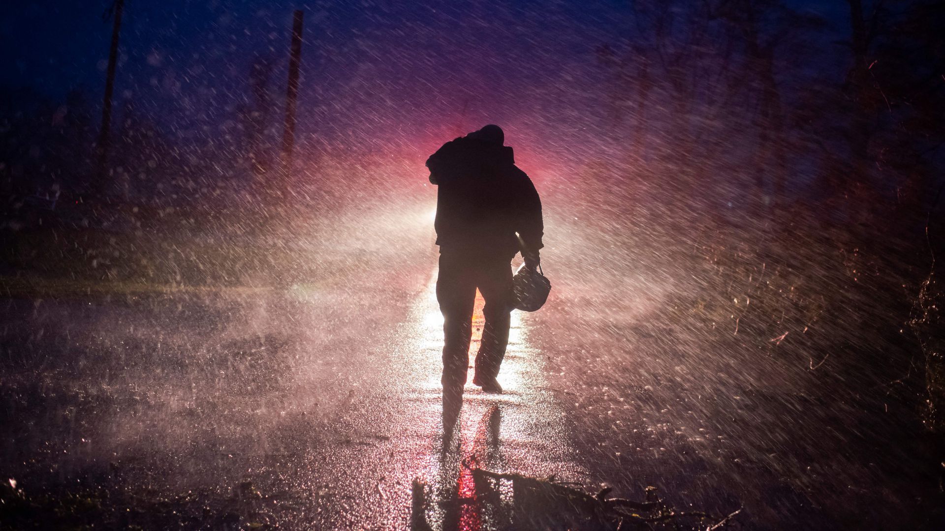 Montegut fire chief Toby Henry walks back to his fire truck in the rain as firefighters cut through trees on the road in Bourg, Louisiana as Hurricane Ida passes on August 29