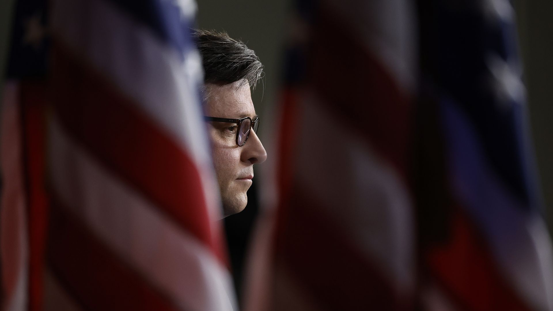 Mike Johnson framed by flags