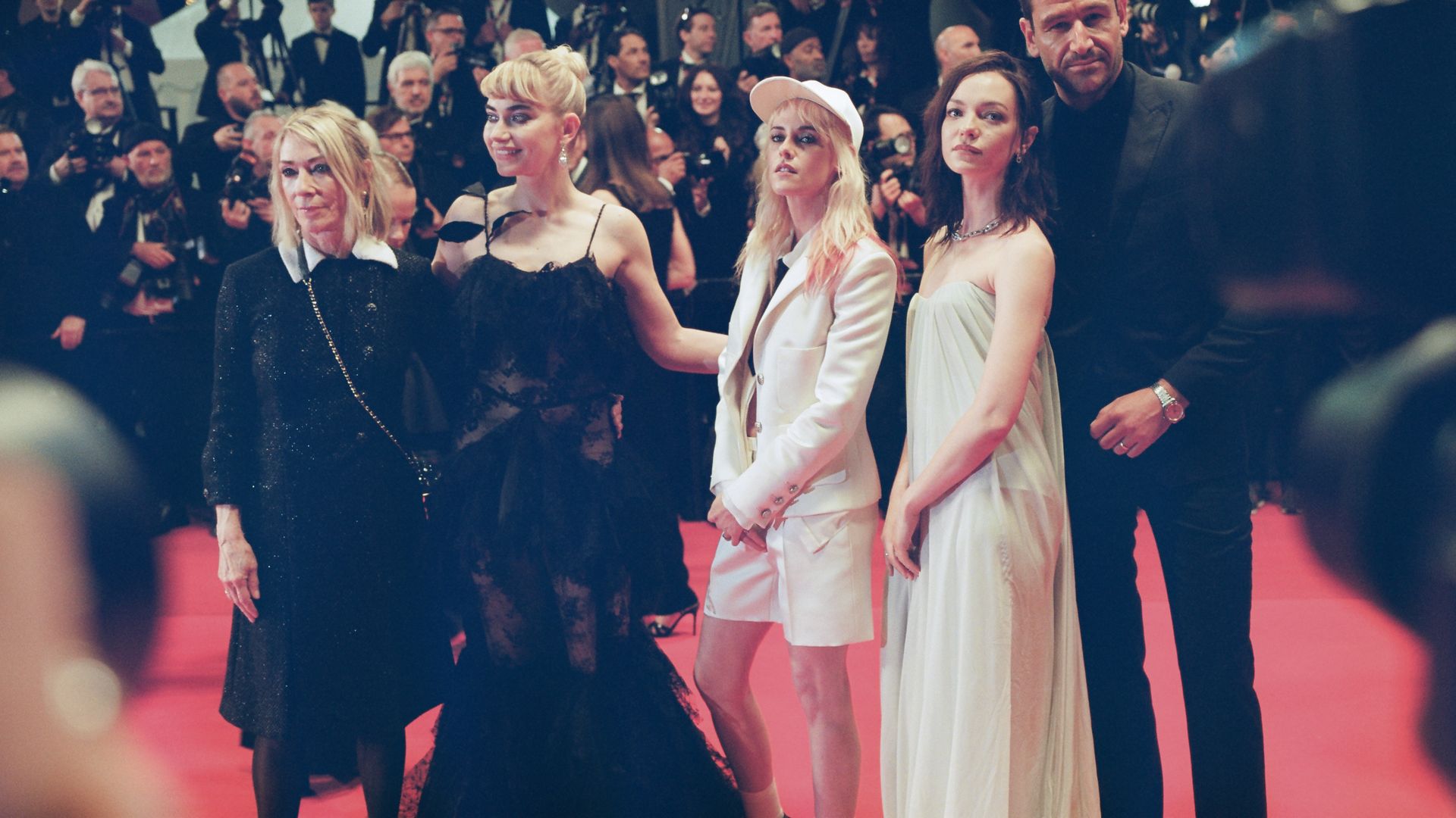 A photo of five people on a red carpet film screening with a wall of photographers behind them.