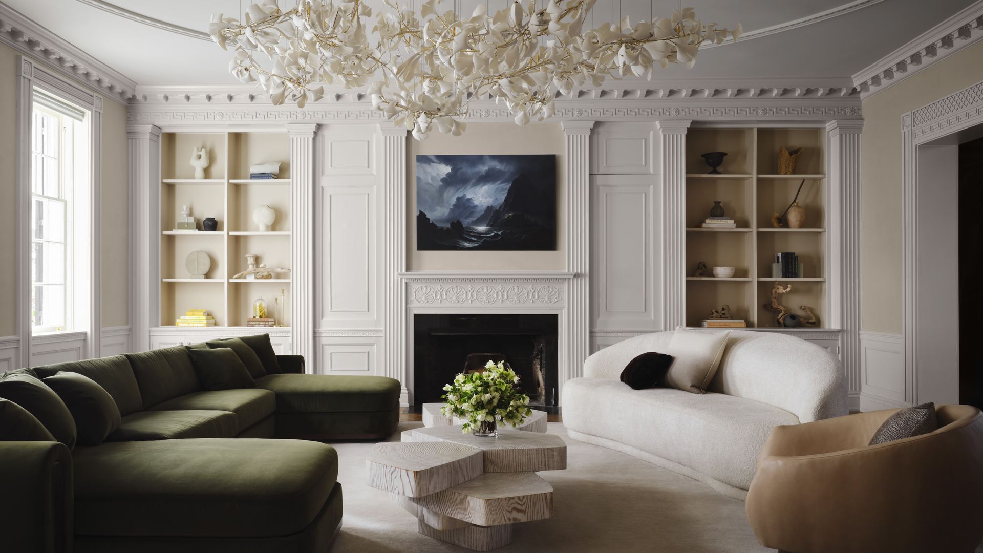A photo showing a living room with couches, a fireplace and a large chandelier.