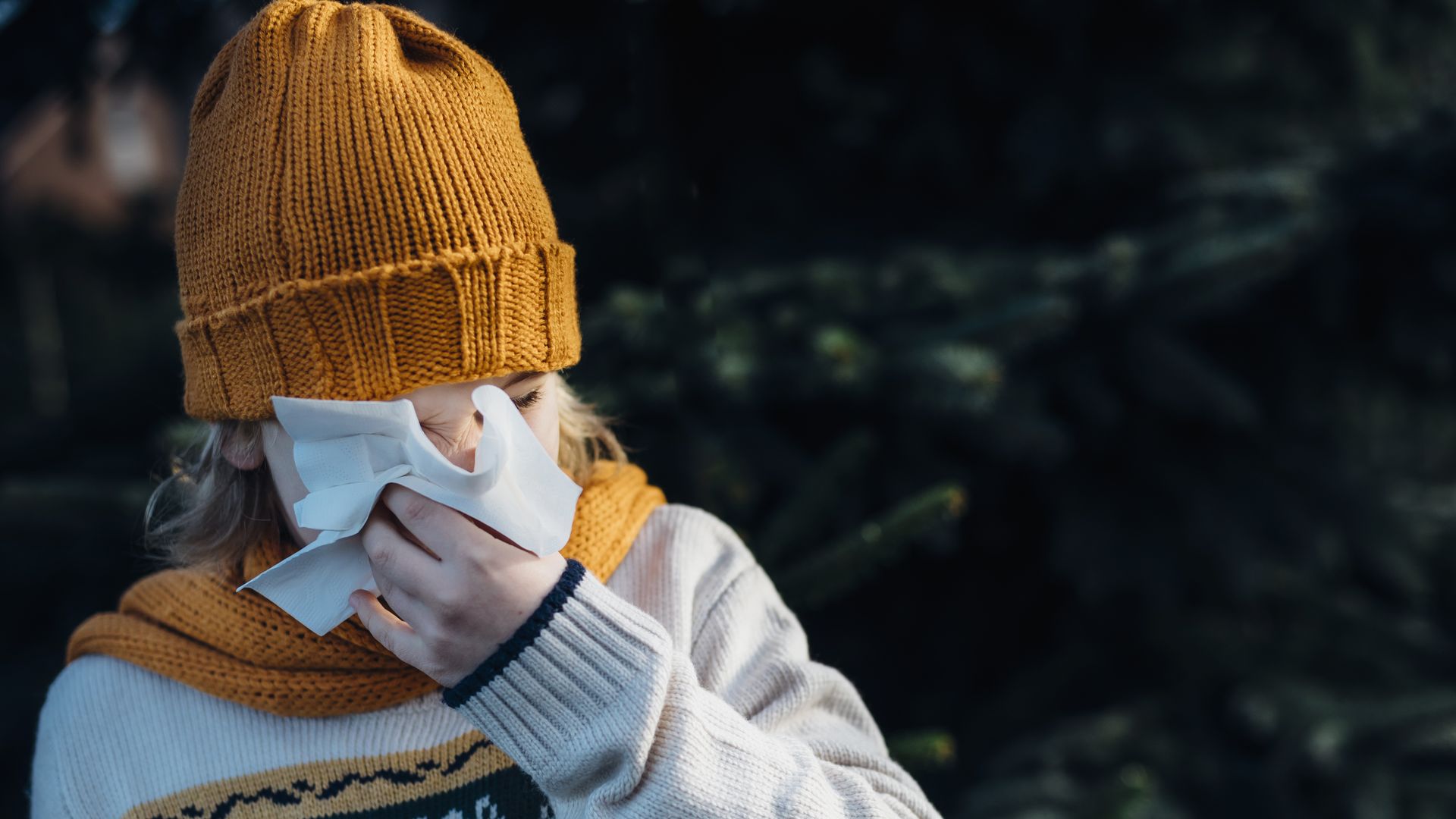 A kid in winter gear blows nose