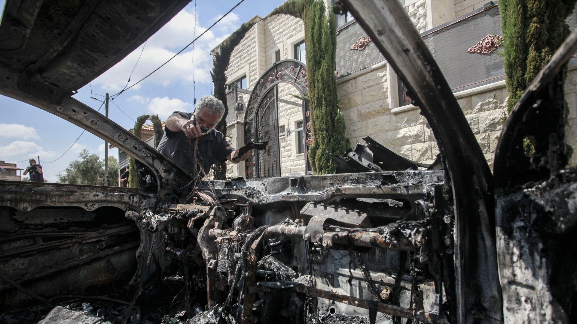 A Palestinian inspects the destroyed car after it was attacked by Jewish settlers in the village of Jit, near Qalqilya, in the northern occupied West Bank.