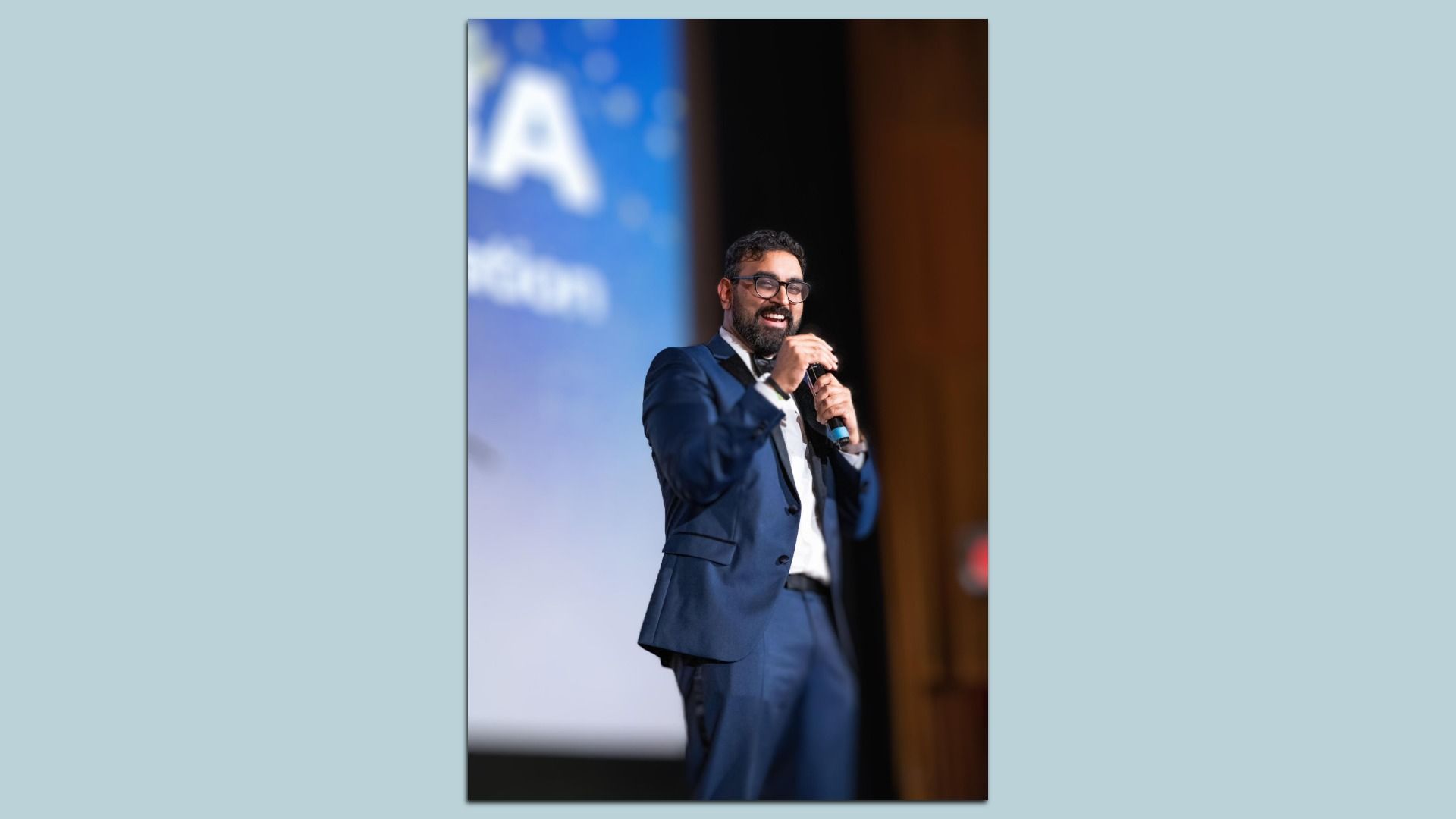 Rohit Molhotra speaks on stage while holding a microphone.