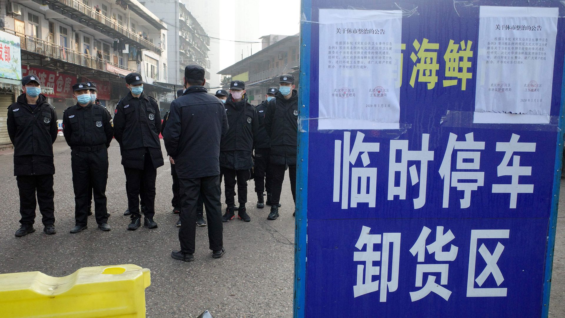 Security guards wearing surgical face masks and standing in front of the closed seafood market in Wuhan, China, where the new virus has been found