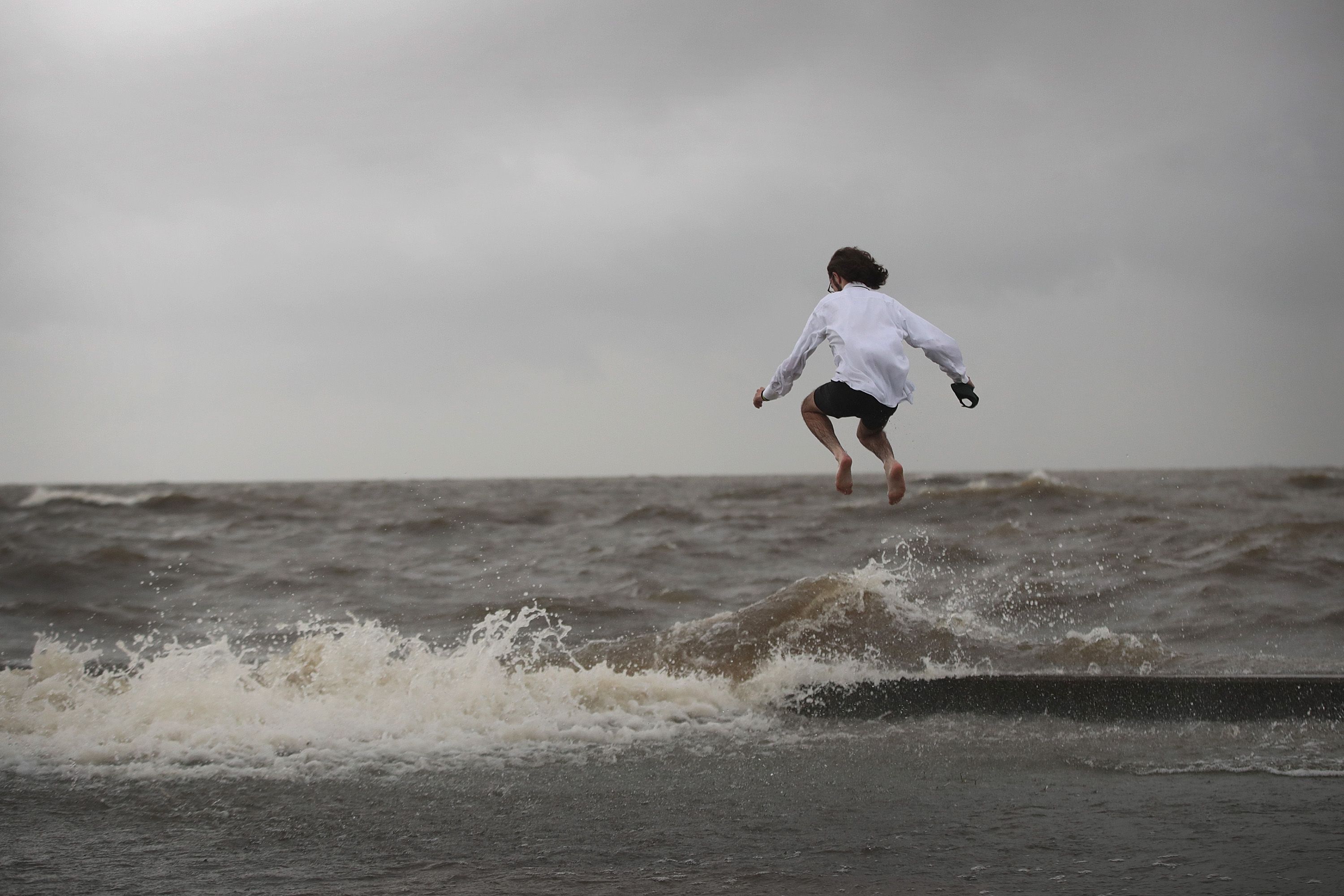 A man jumps a wave as it breaks against a floodwall in a park along the shore of Lake Pontchartrain after the area flooded in the wake of Hurricane Barry on July 13.