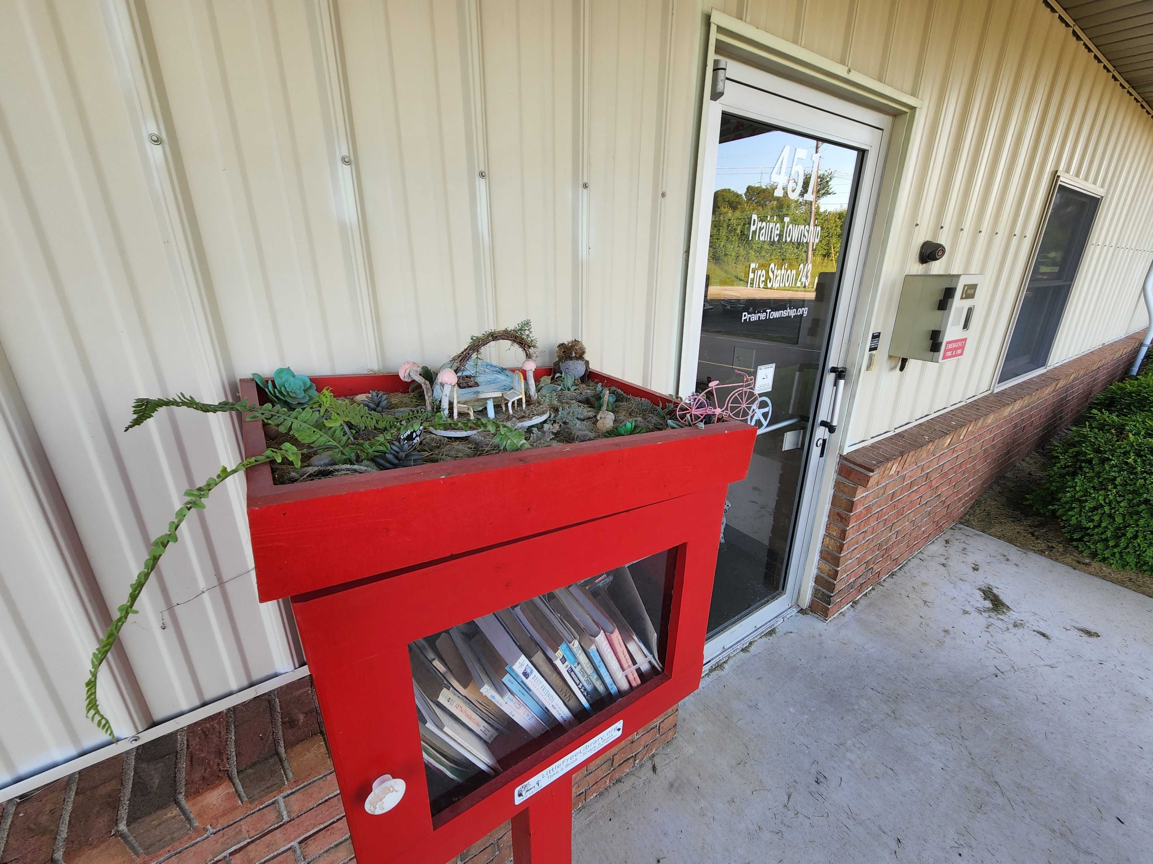 A Little Free Library with a fairy garden on top.