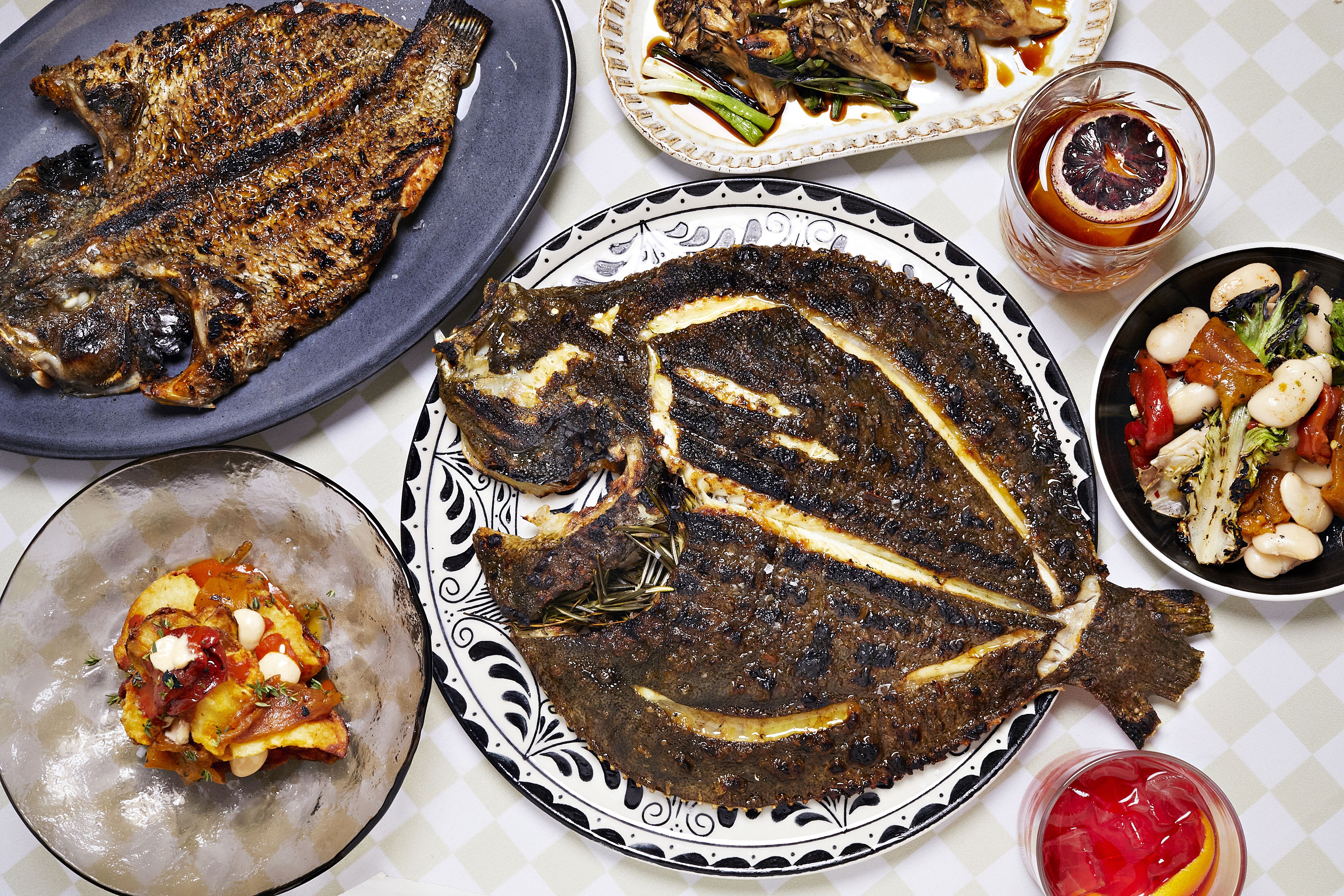 A whole dorade fish on a table with sides and sangria