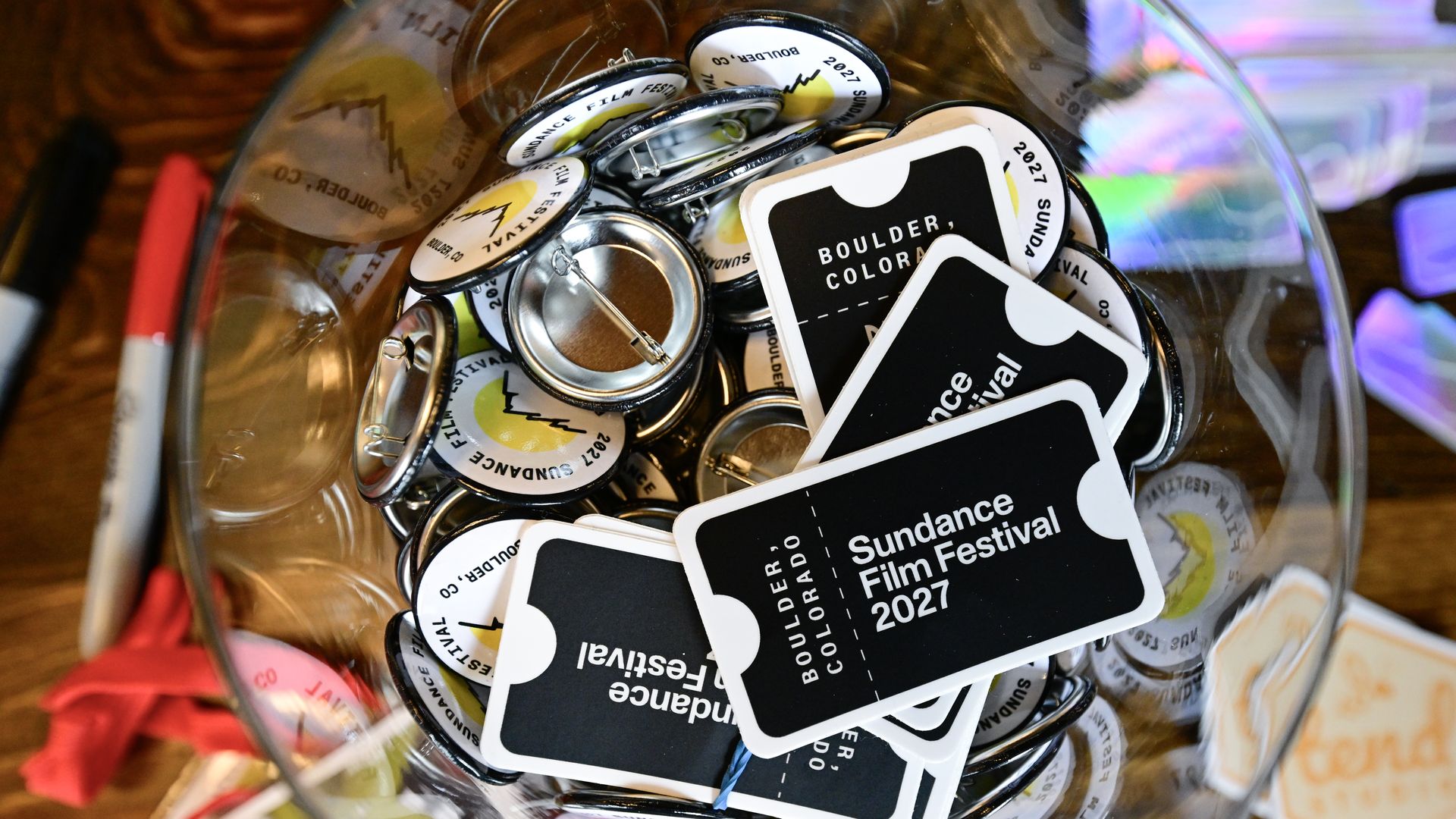 Sundance Film Festival buttons and stickers announcing the festival's move to Boulder sit in a glass bowl.