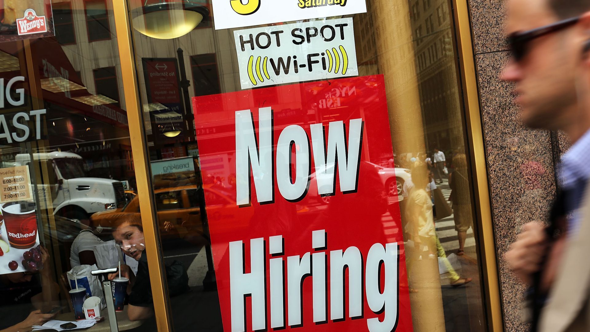 A now hiring sign in a window
