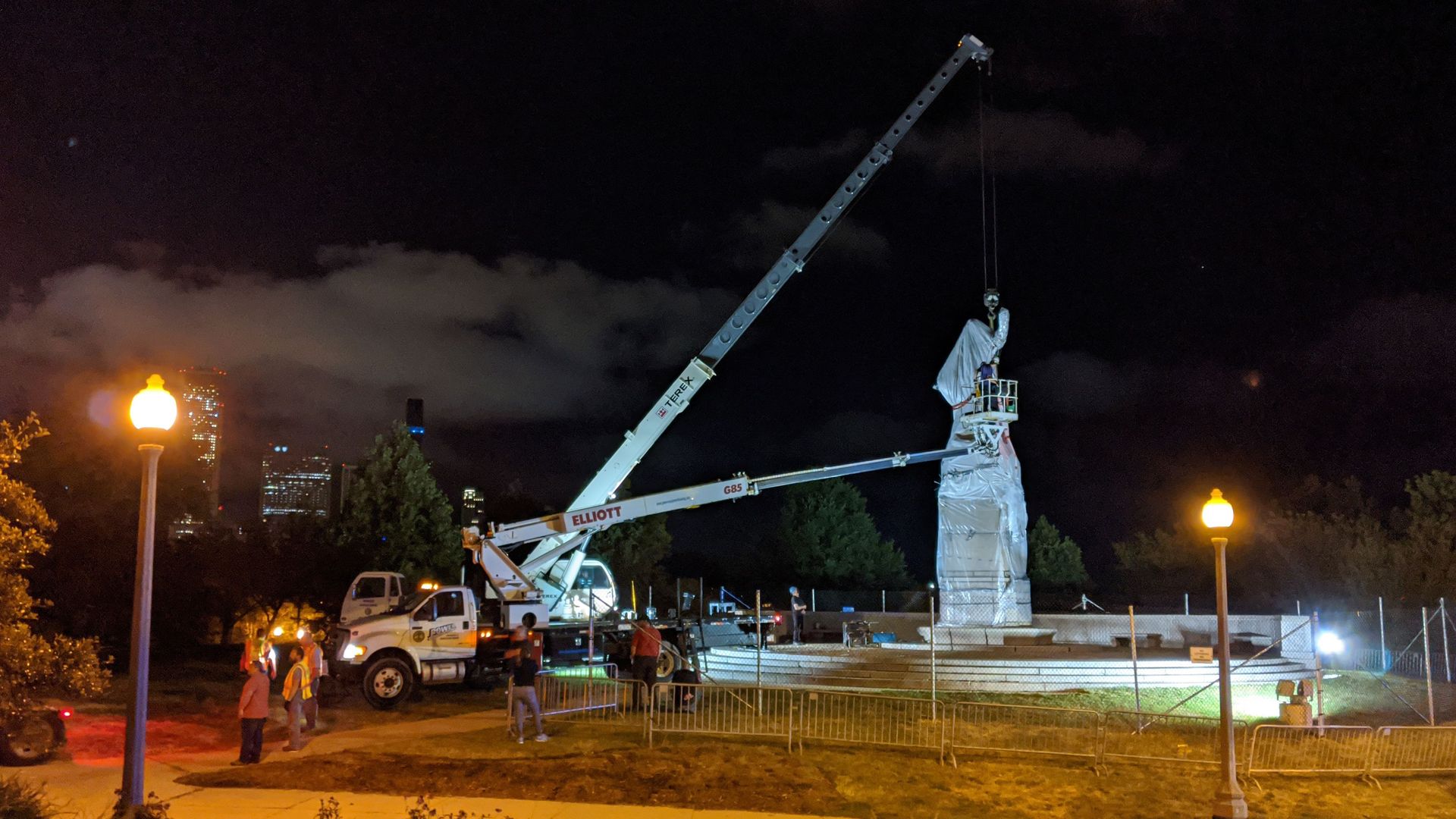 Photo of construction cranes removing a statue.