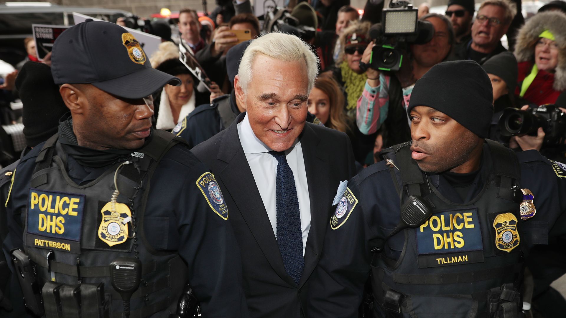 Roger Stone between to law enforcement officers.