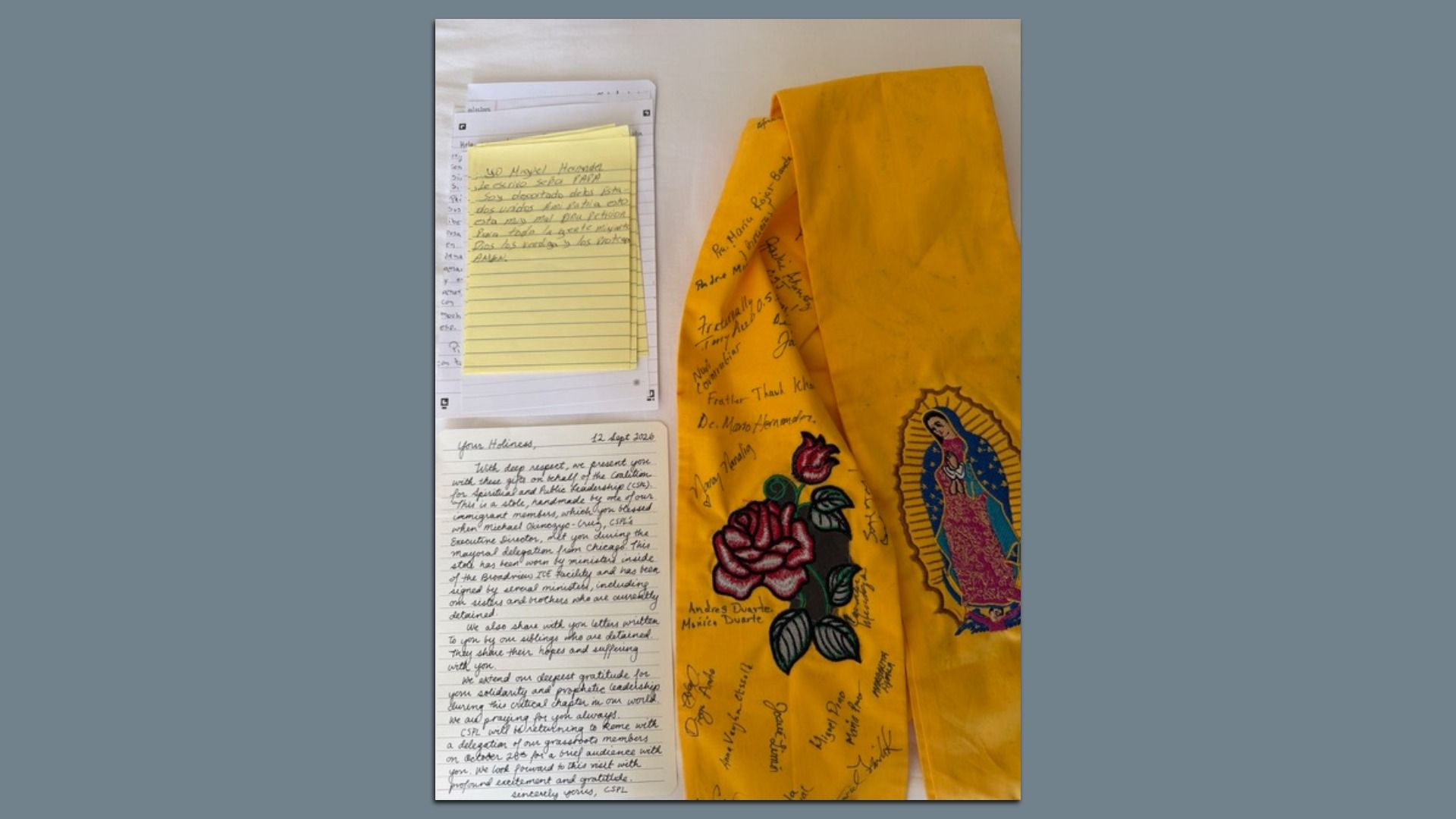 Yellow devotional scarf featuring the Virgin of Guadalupe, covered in handwritten signatures. To the left are white notebook pages with a stack of yellow sticky notes.