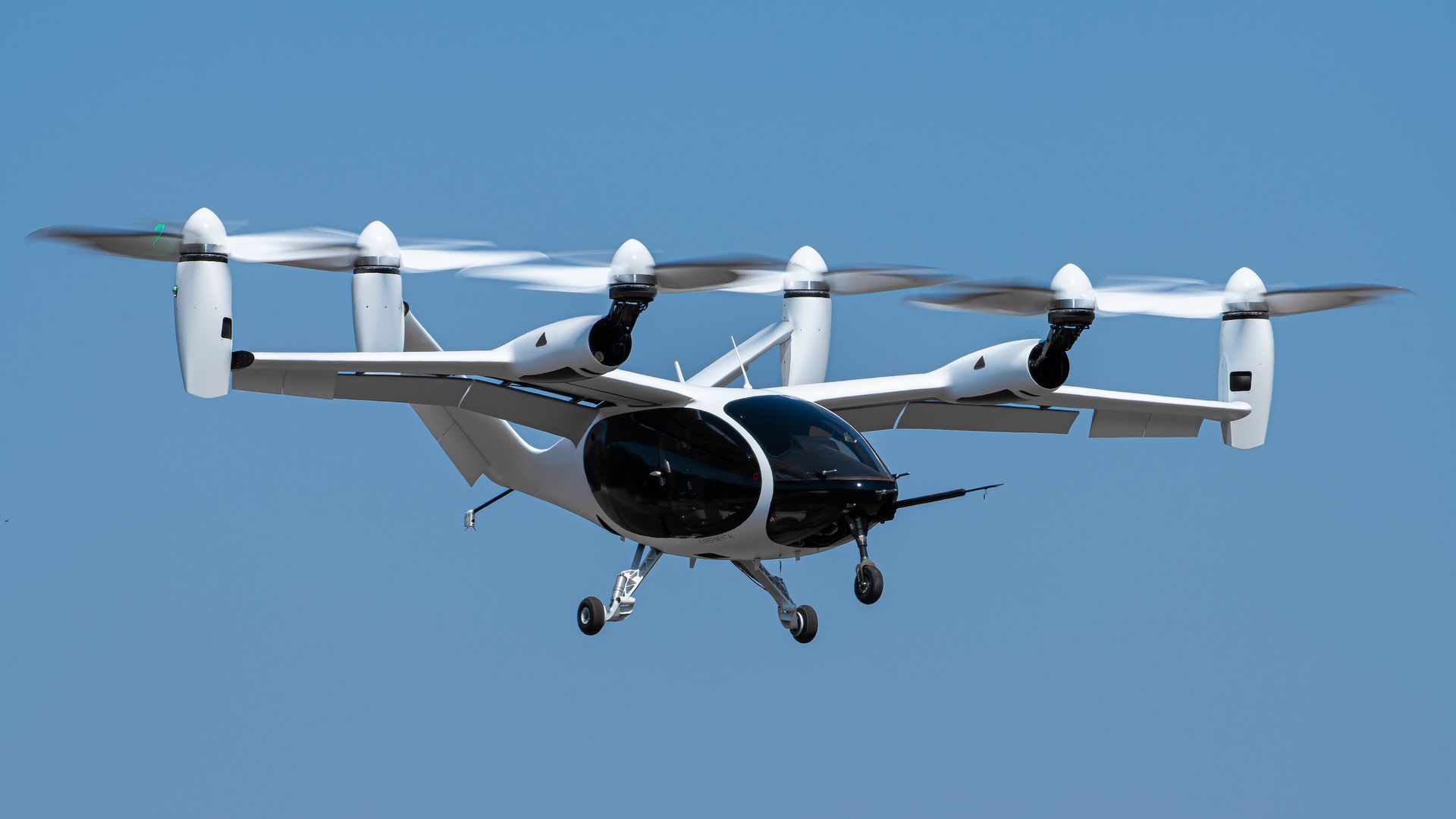 Photo of Joby Aviation's "flying car" aircraft in the air over some trees.