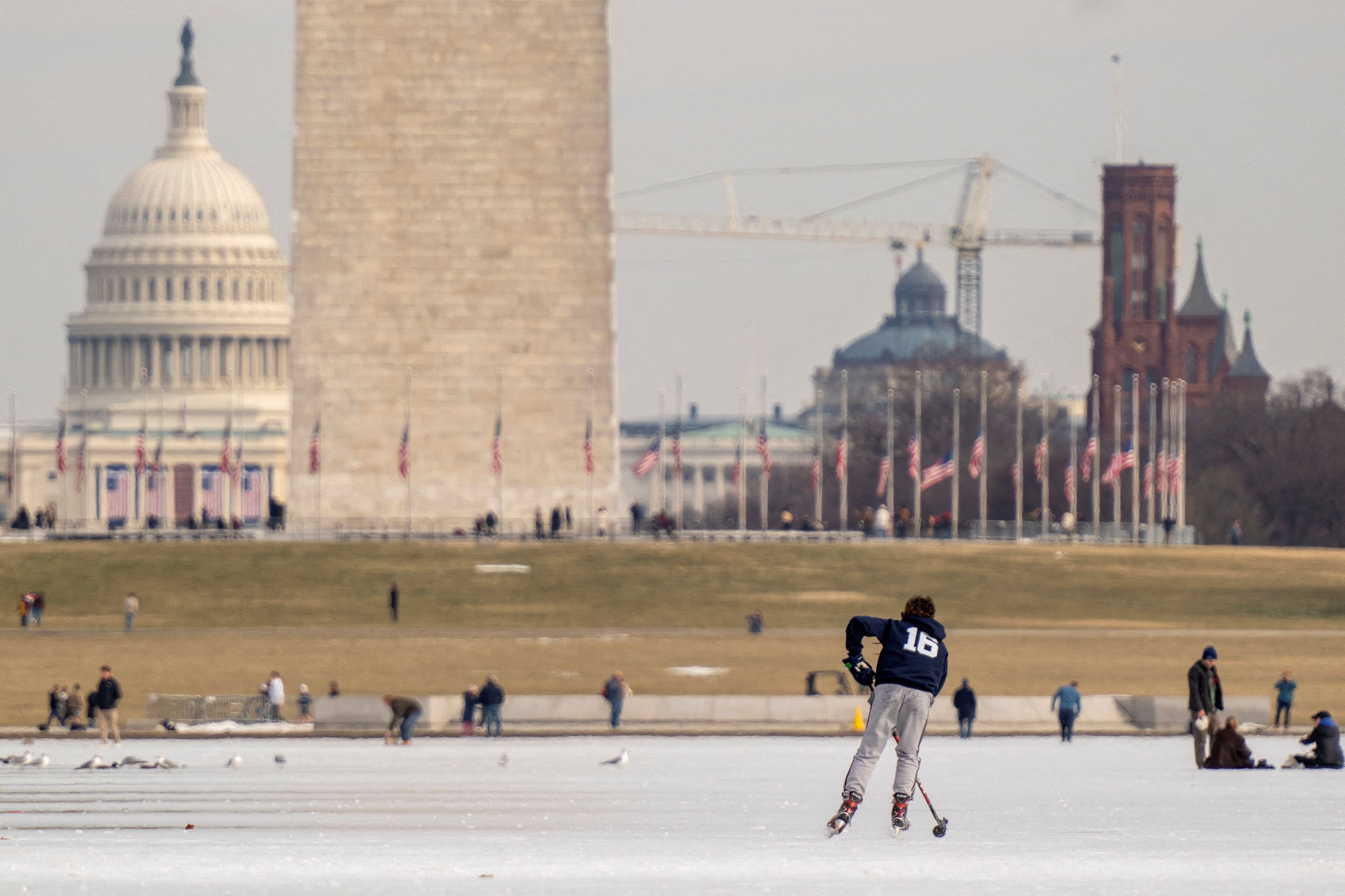 he U.S Capitol and Washington Monument are seen in the background as people walk and skate on the ice-covered reflecting pool on the National Mall in Washington, U.S., January 26, 2025. REUTERS/Ken Cedeno