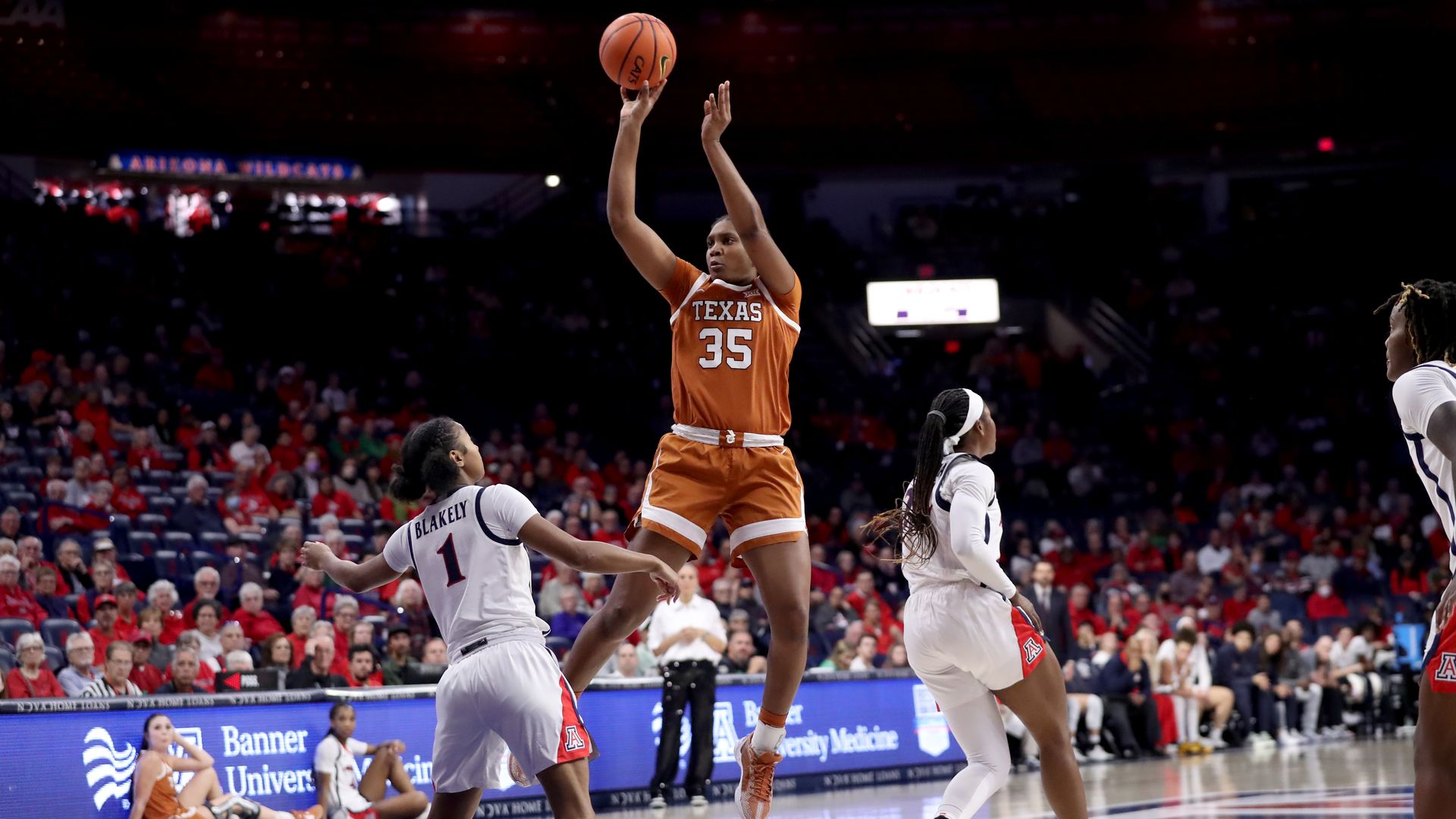 A University of Texas basketball player shoots the ball over a defender.