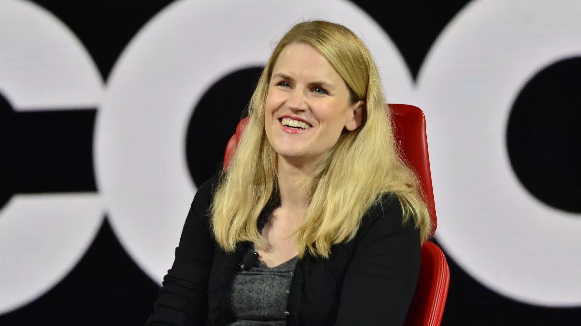 Photo of Frances Haugen in a black sweater sitting in a red chair