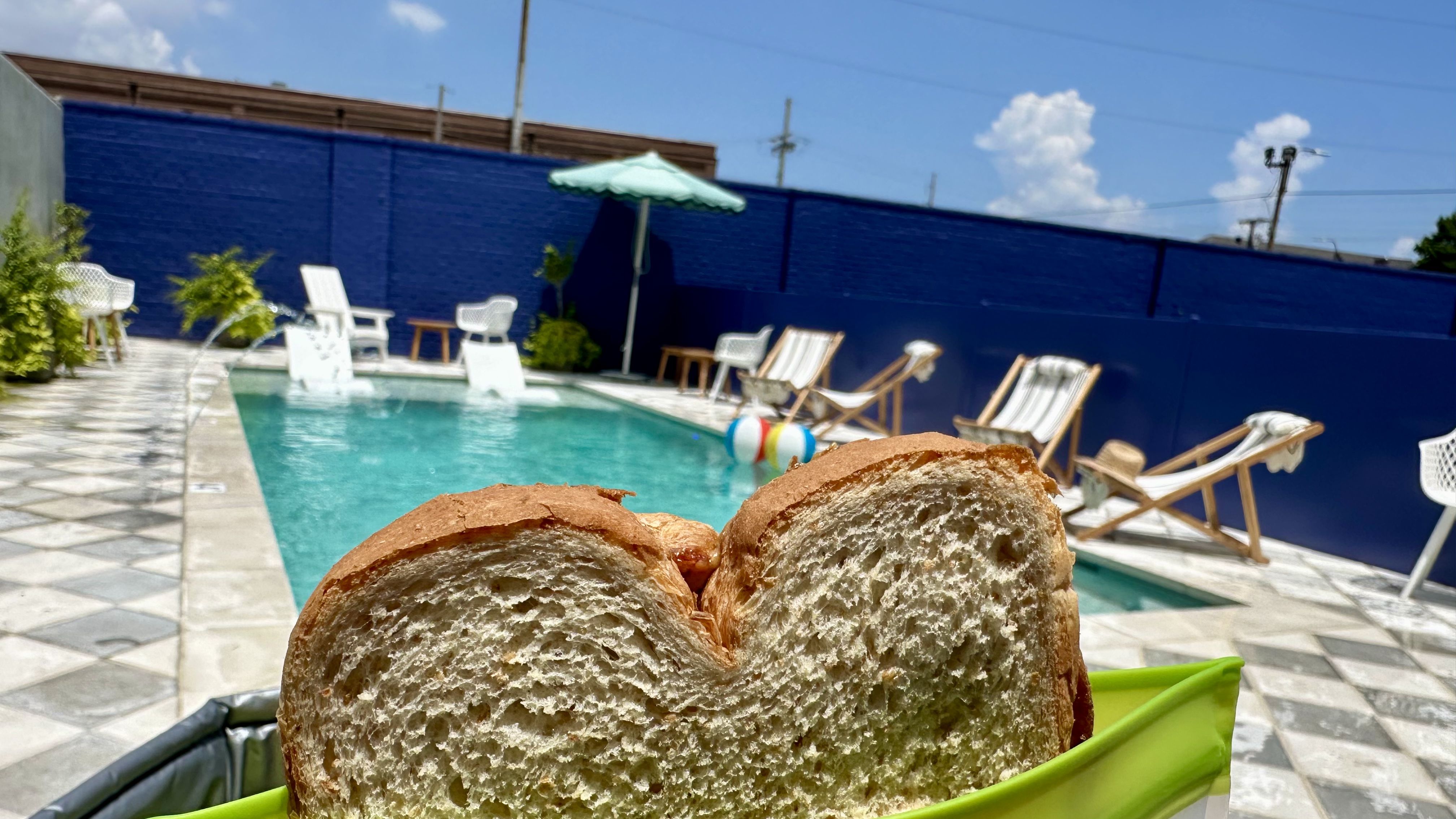 Photo shows a peanut butter and jelly sandwich in front of a pool.