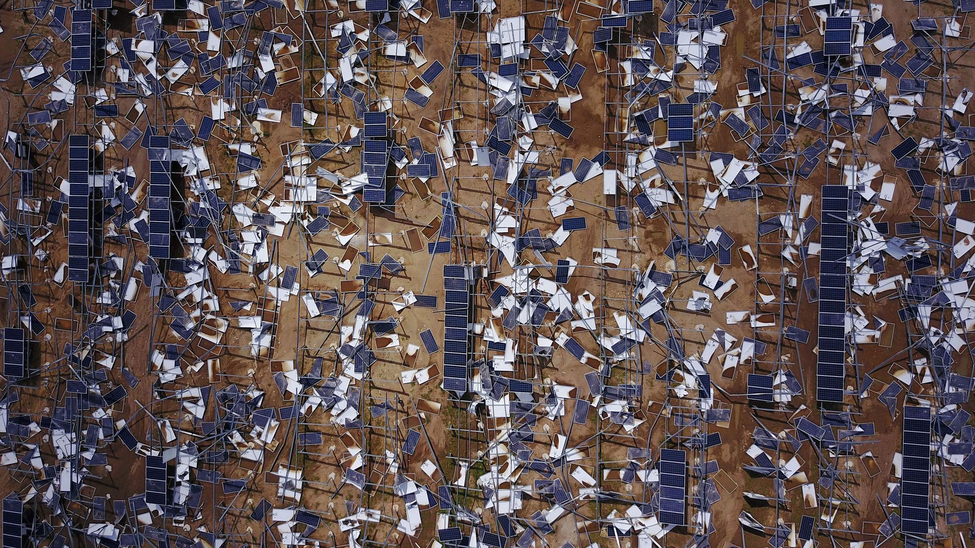 This is a birds eye view of destroyed solar panels in a dirt field. 