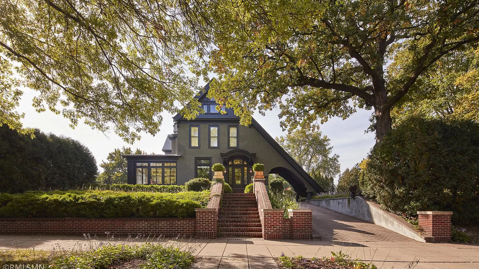 A large green house with a long slanted roof, as seen in summer.