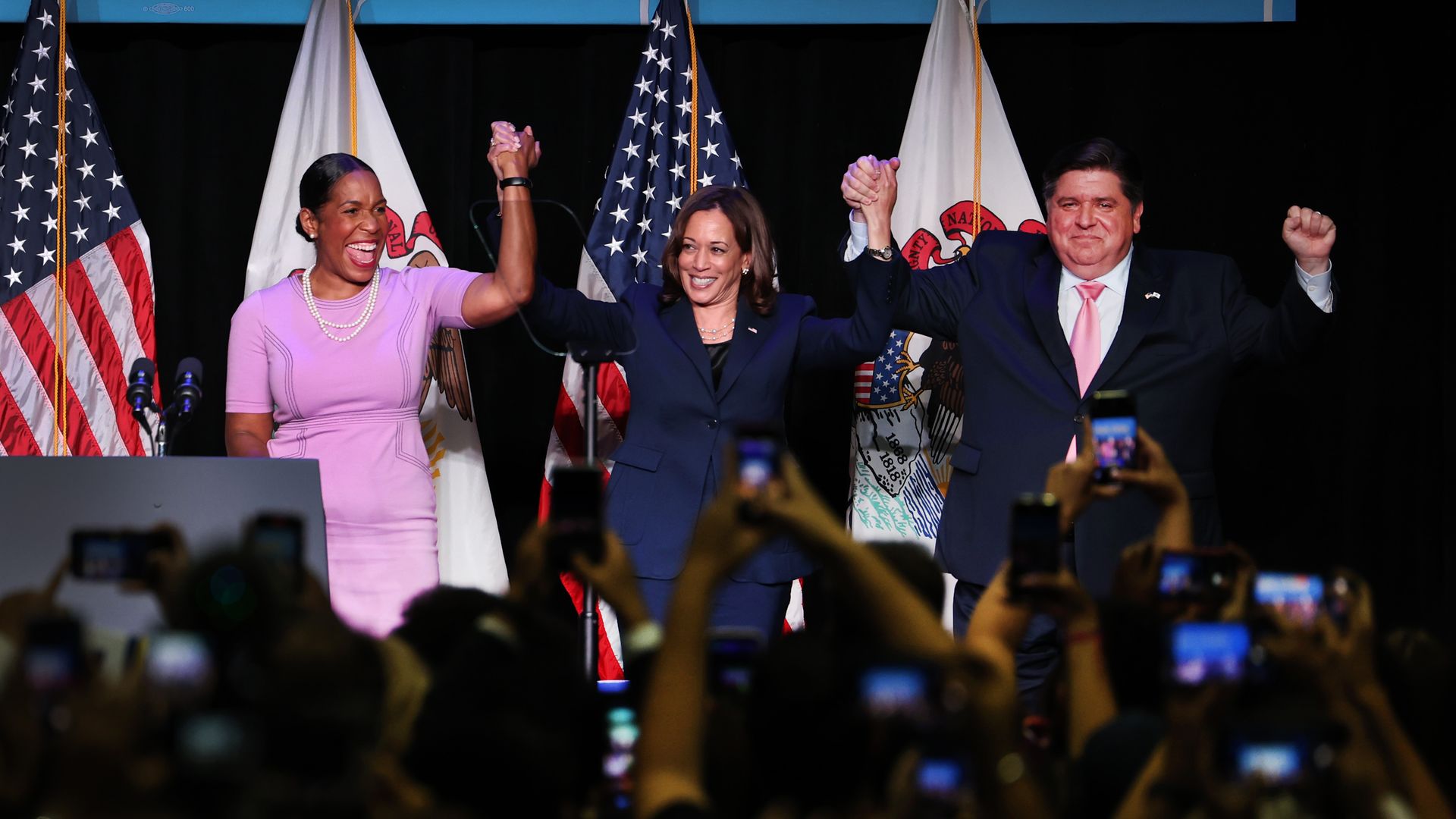 Photo of three people holding hands on stage 