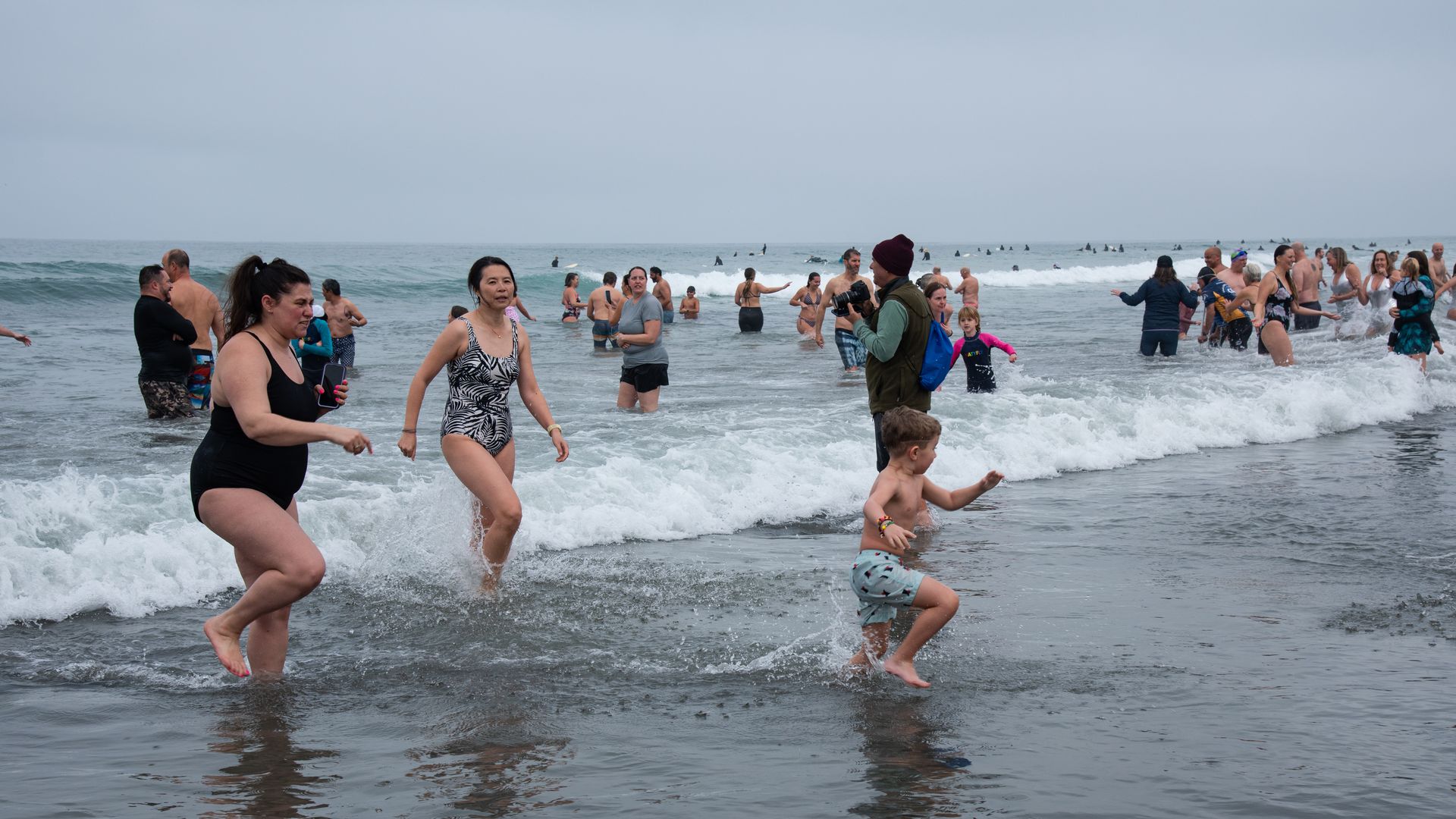 People run out of the water in the winter after a polar plunge.