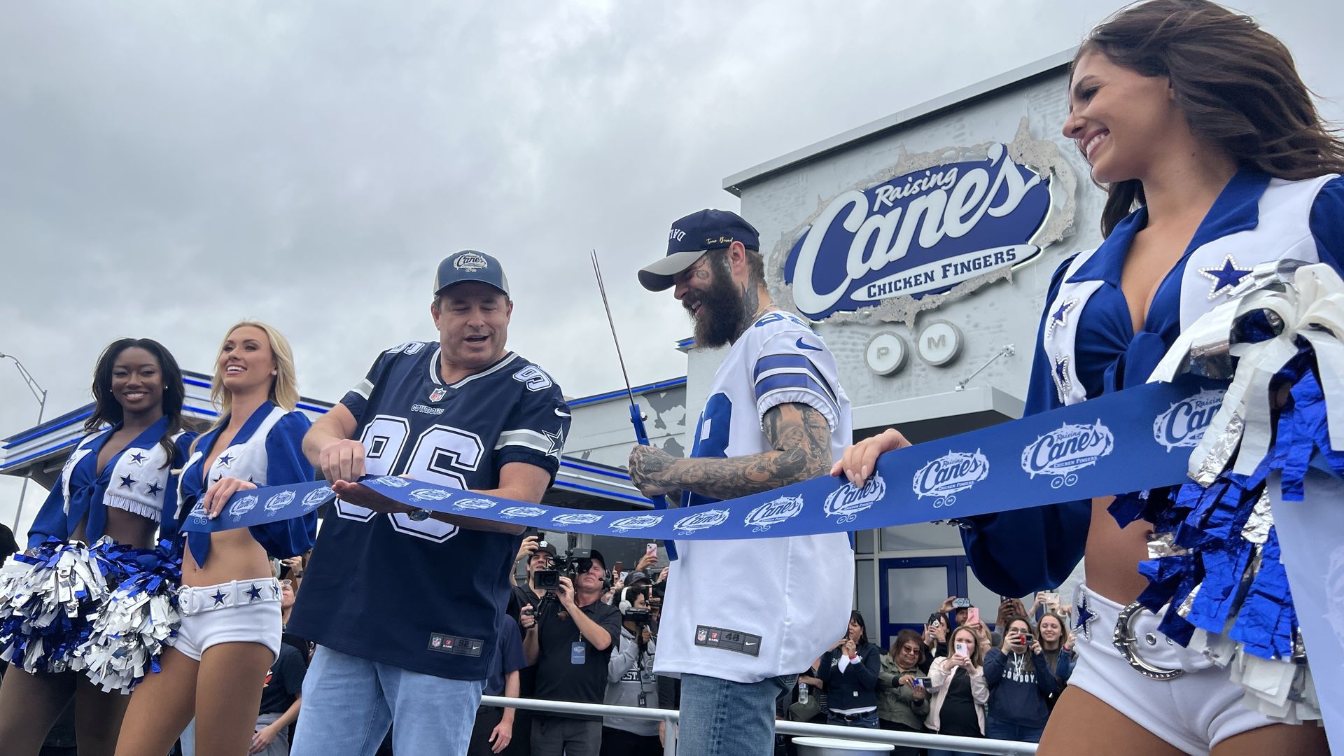a photo of Post Malone cutting a ribbon at an updated Raising Cane's