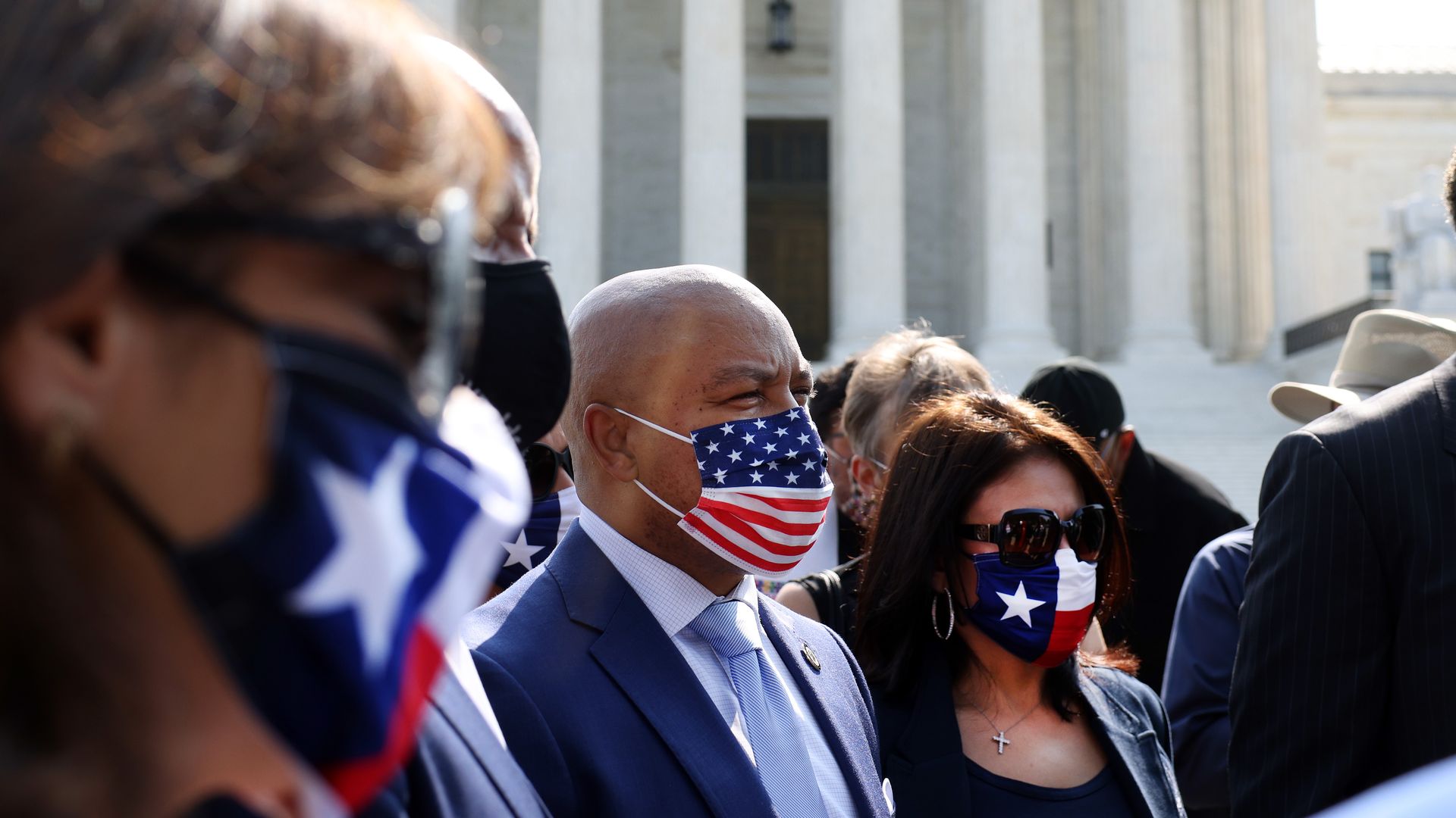 Photo of people wearing masks with the American and Texas flag designs 