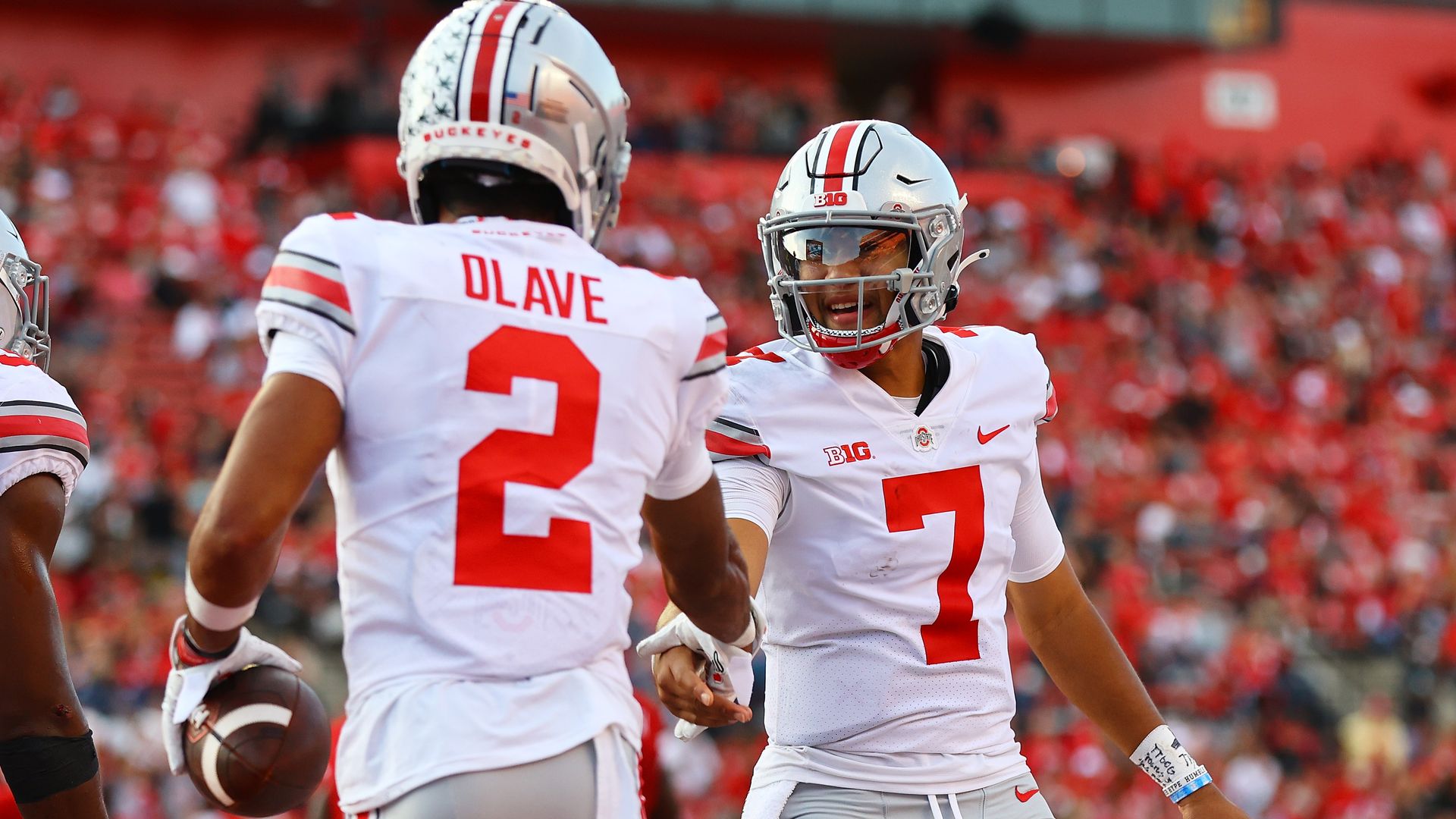 Two football players shake hands in celebration after a touchdown.